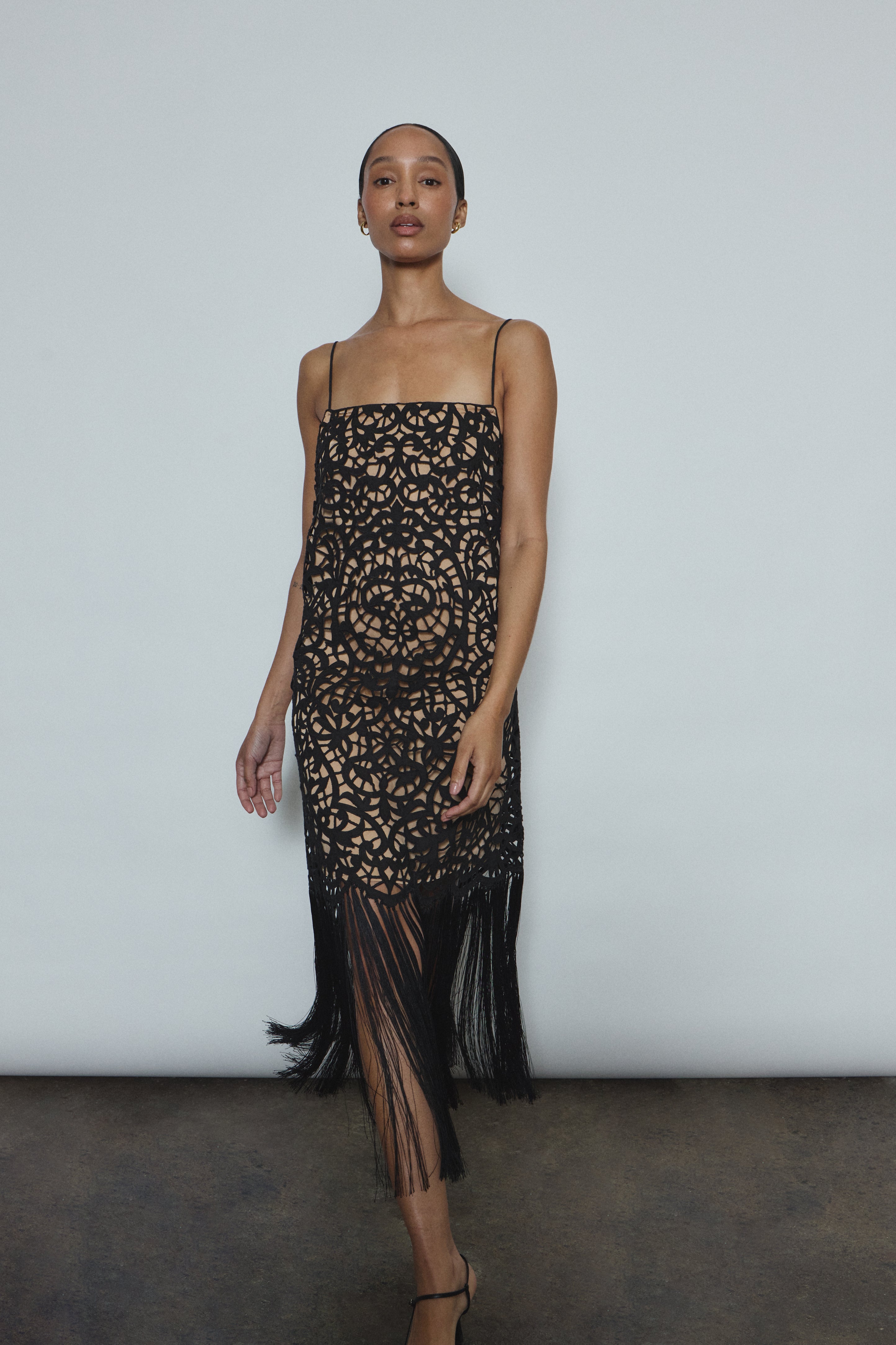 Detail of the intricately cut openwork cotton motif and hand-applied fringe on the black Kamperett Lenore Dress.