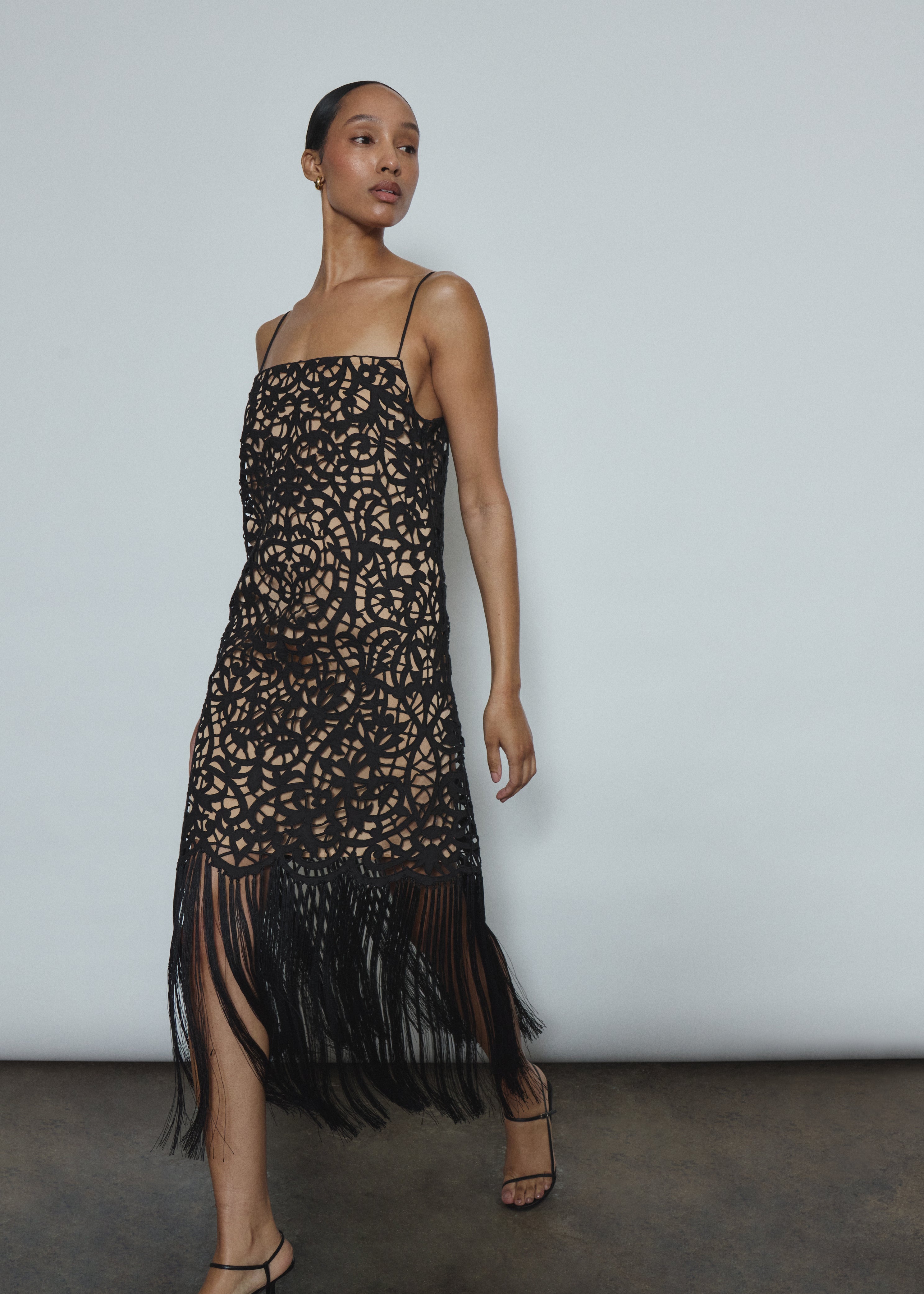 Editorial image of a model wearing the black Kamperett Lenore Dress, a modern occasion A-line midi with openwork motif.