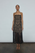 Front view of a model wearing the black cotton openwork Kamperett Lenore Dress, an A-line midi with square neckline, spaghetti straps, and hand-applied fringe.
