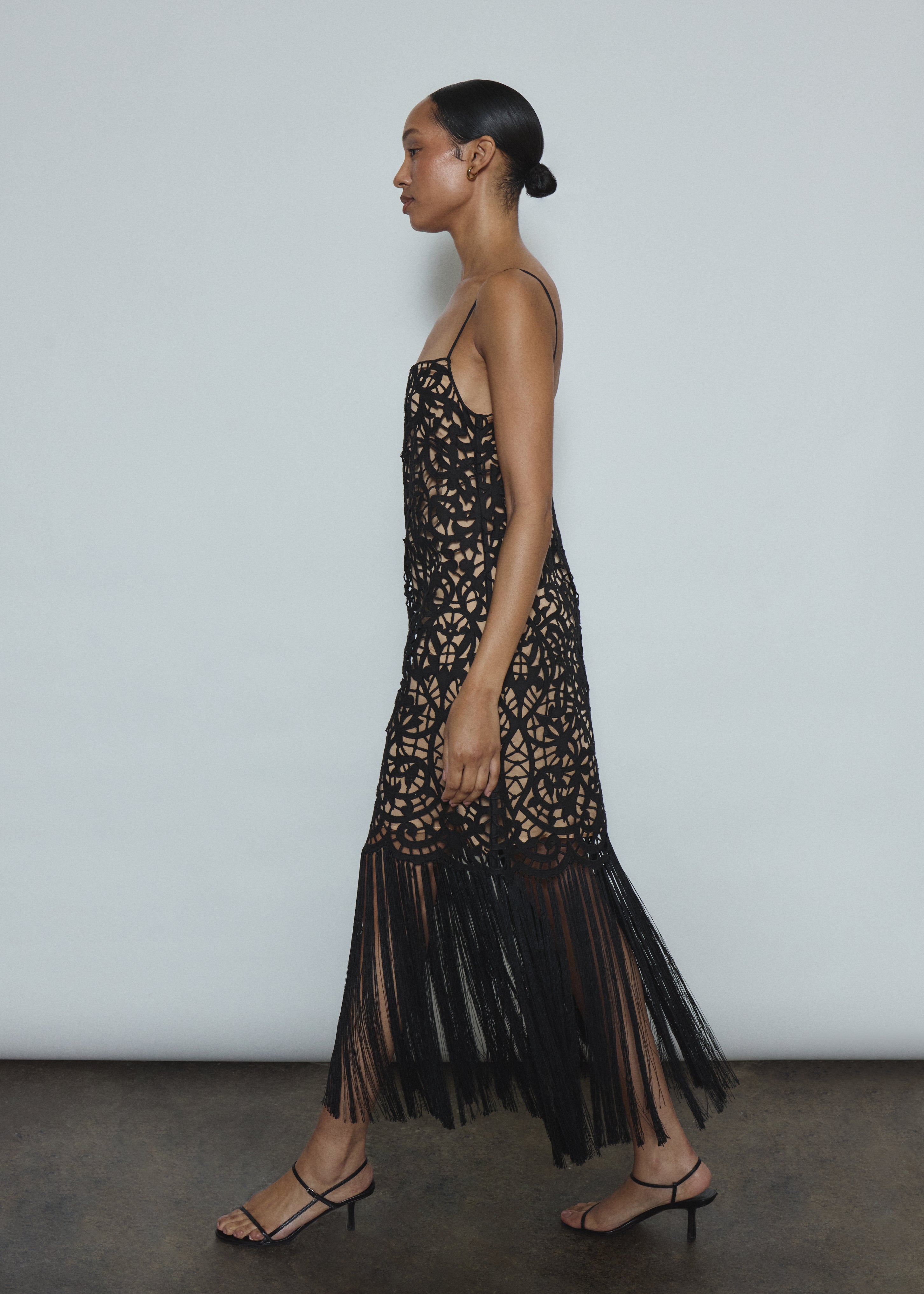 Side view of the black cotton openwork Kamperett Lenore Dress showing the A-line silhouette and fringe-trimmed hem.