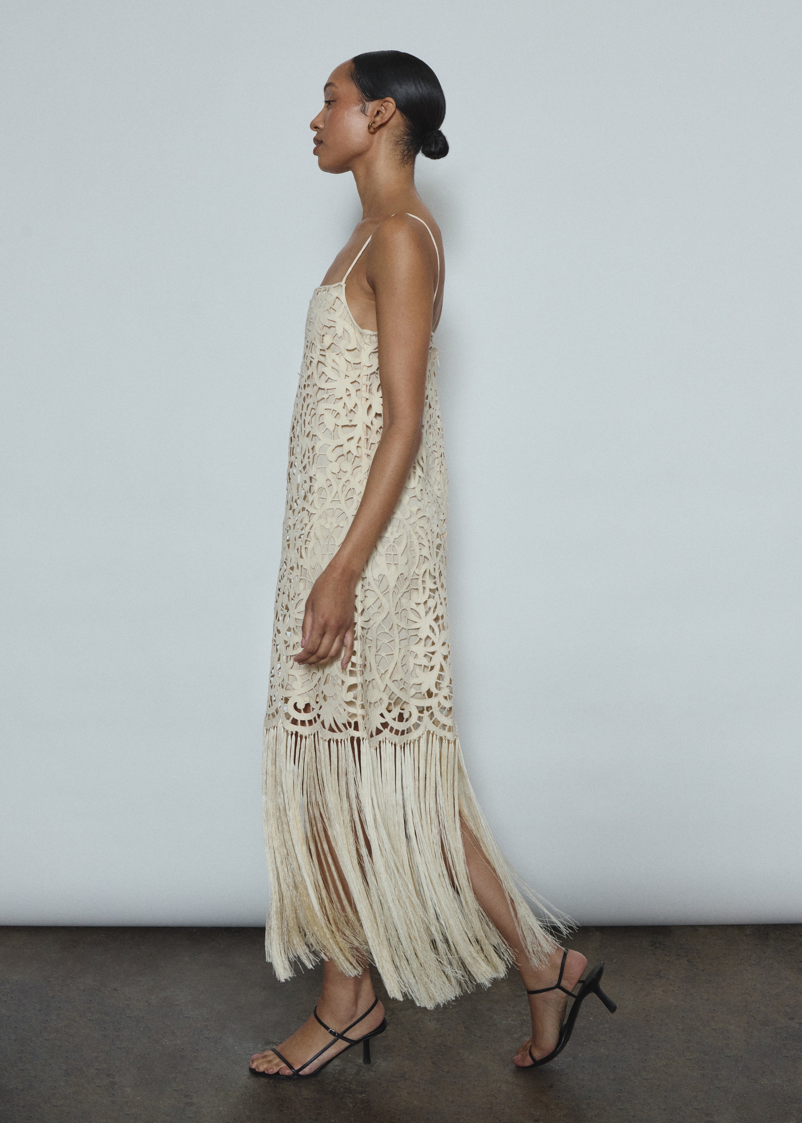 Detail of the intricately cut openwork cotton motif and hand-applied fringe on the cream Kamperett Lenore Dress.