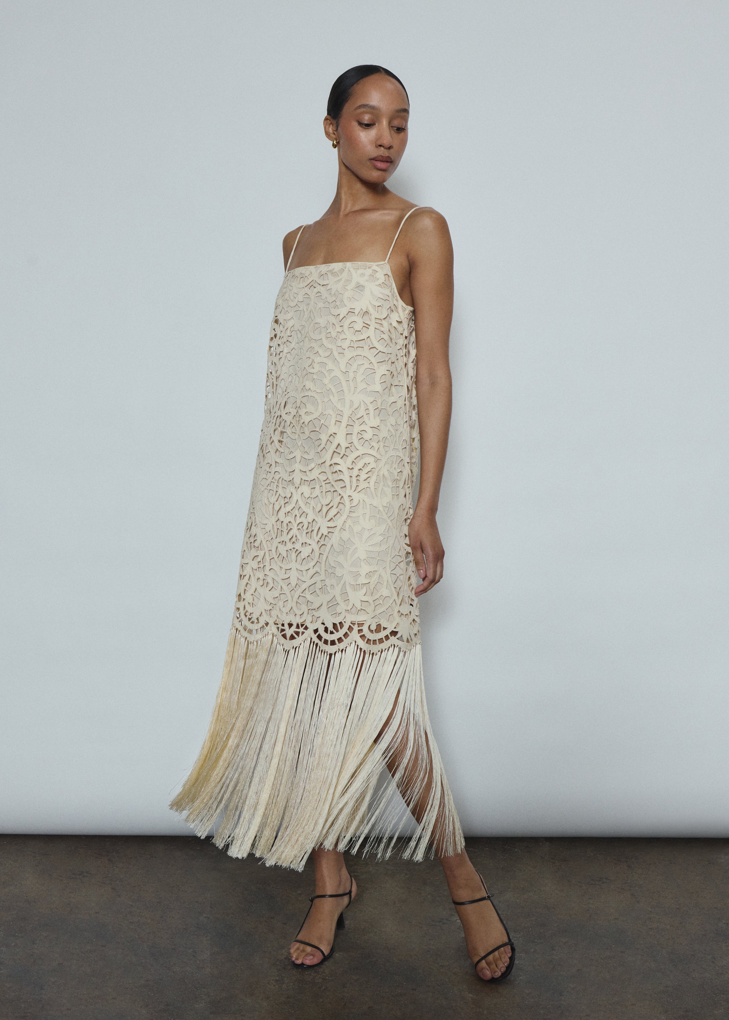 Side view of the cream cotton openwork Kamperett Lenore Dress showing the A-line silhouette and fringe-trimmed hem.