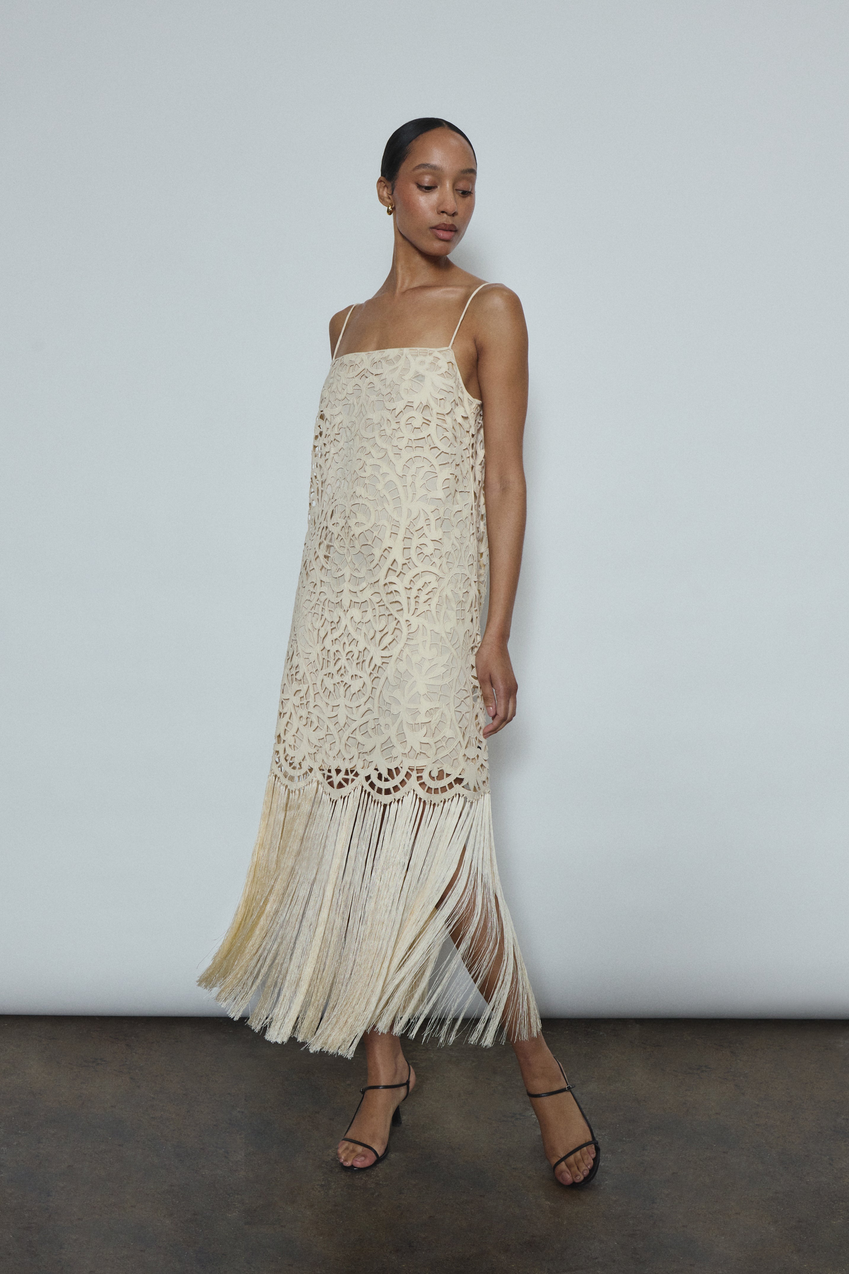 Side view of the cream cotton openwork Kamperett Lenore Dress showing the A-line silhouette and fringe-trimmed hem.
