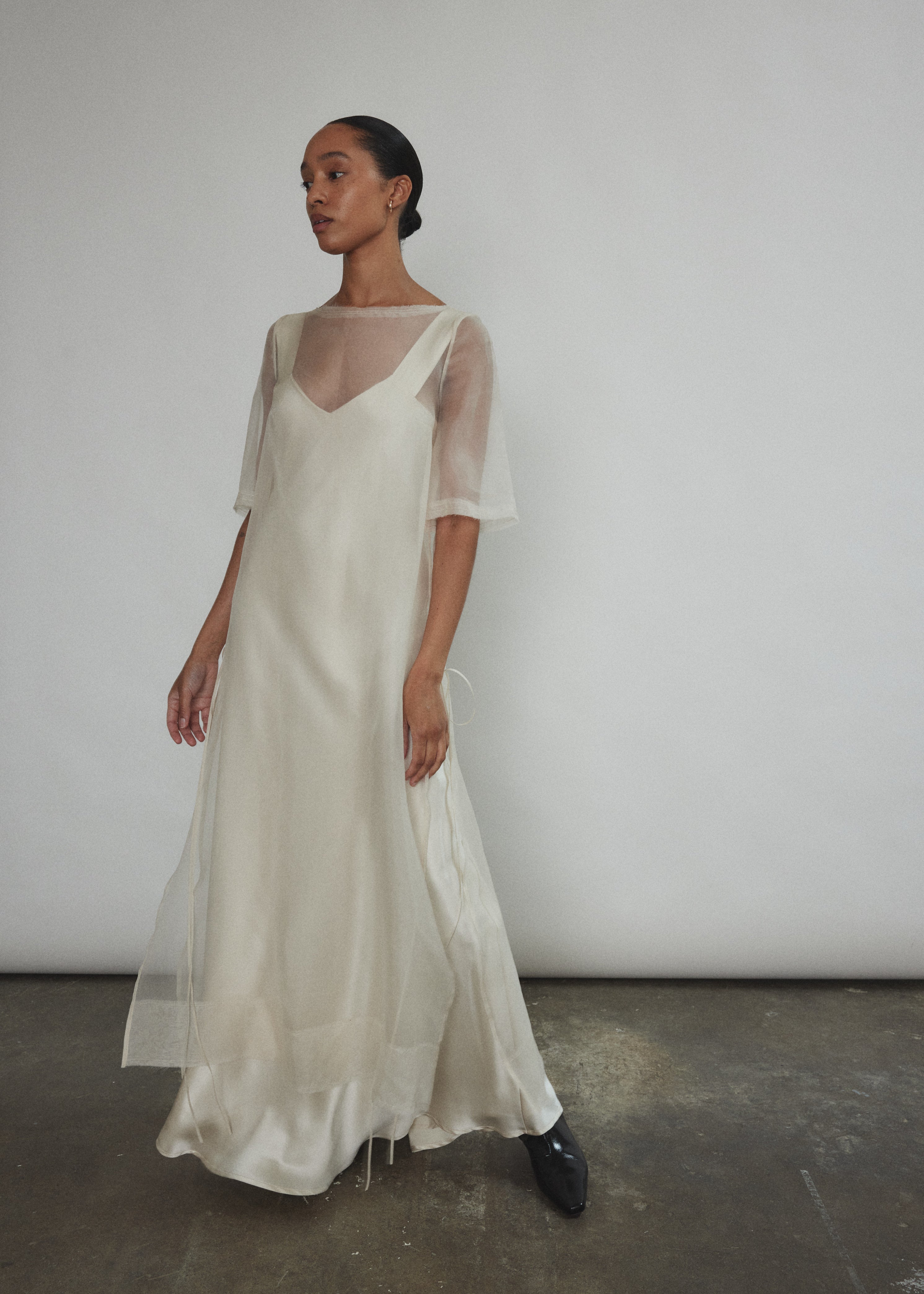 Motion shot of the ivory silk charmeuse Kamperett Lisette Maxi Slip Dress, capturing the fluid bias-cut drape.