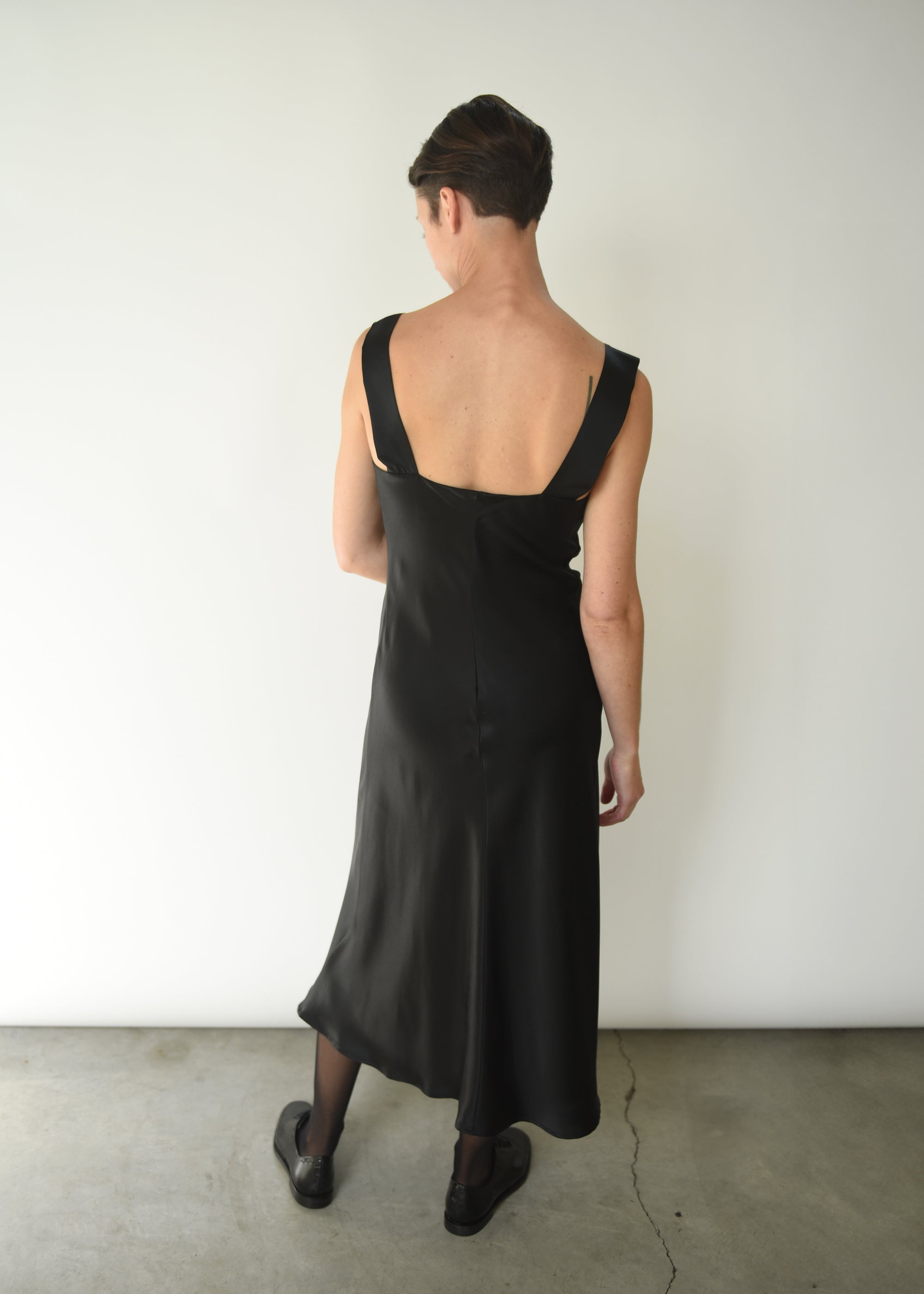 Back view of the black silk charmeuse Kamperett Lisette Midi Slip Dress with straight-cut back and wider straps.