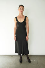 Front view of a model wearing the black silk charmeuse Kamperett Lisette Midi Slip Dress with V-neck and wider straps.