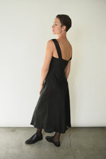 Side view of the black silk charmeuse Kamperett Lisette Midi Slip Dress, showing the bias-cut drape.