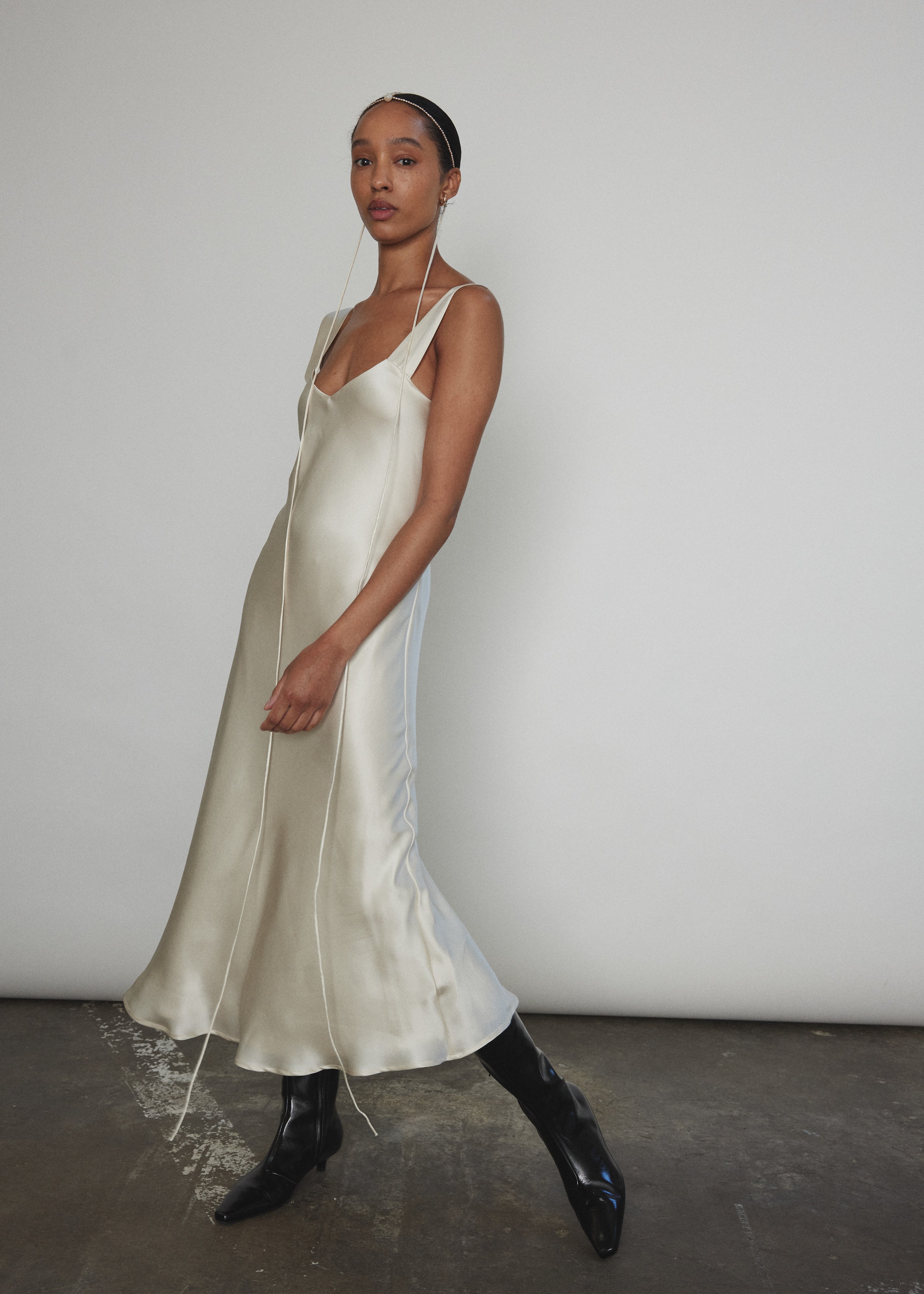 Angled view of the ivory silk charmeuse Kamperett Lisette Midi Slip Dress with V-neck detail.