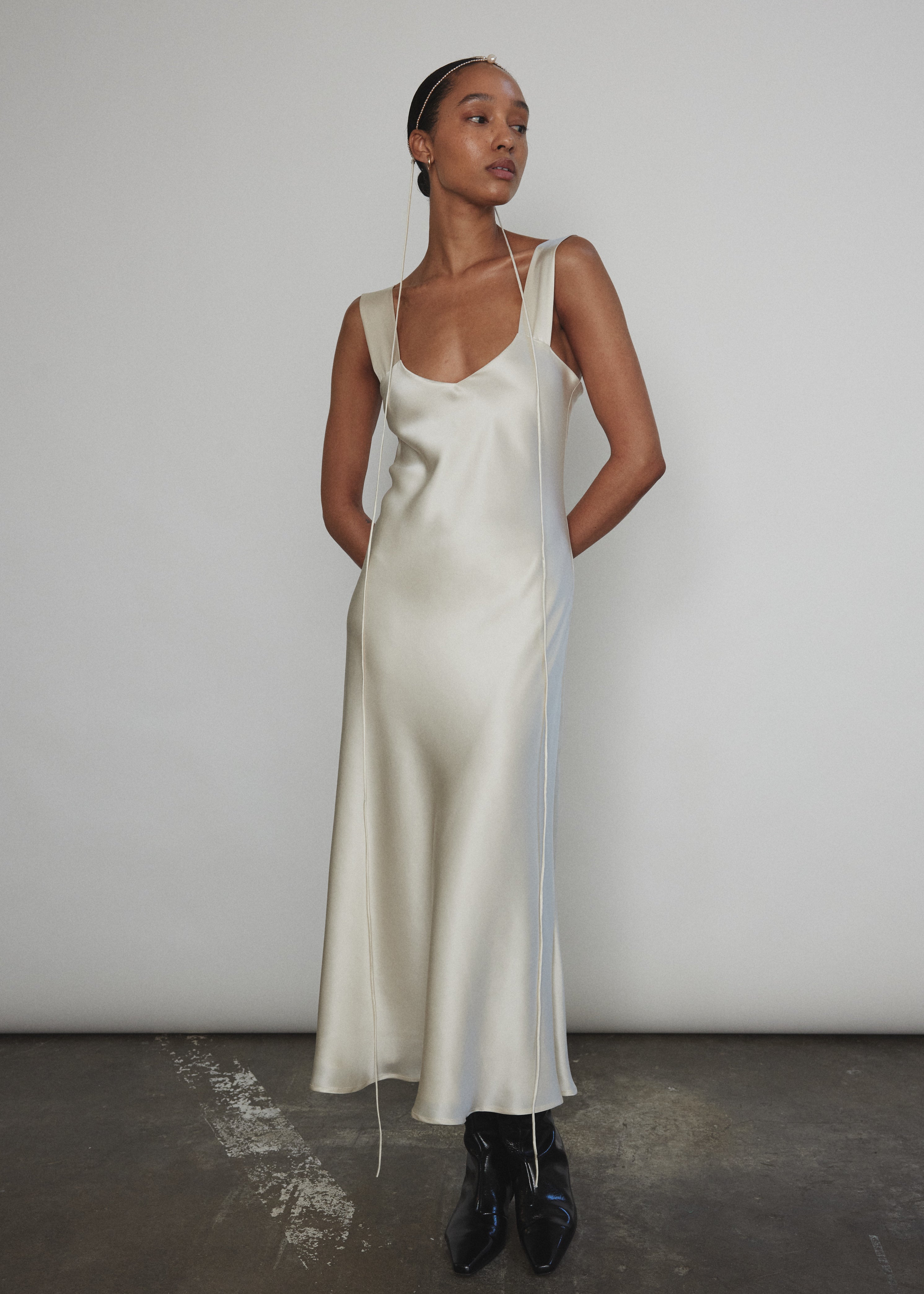 Front view of a bride wearing the ivory silk charmeuse Kamperett Lisette Midi Slip Dress with V-neck and wider straps.