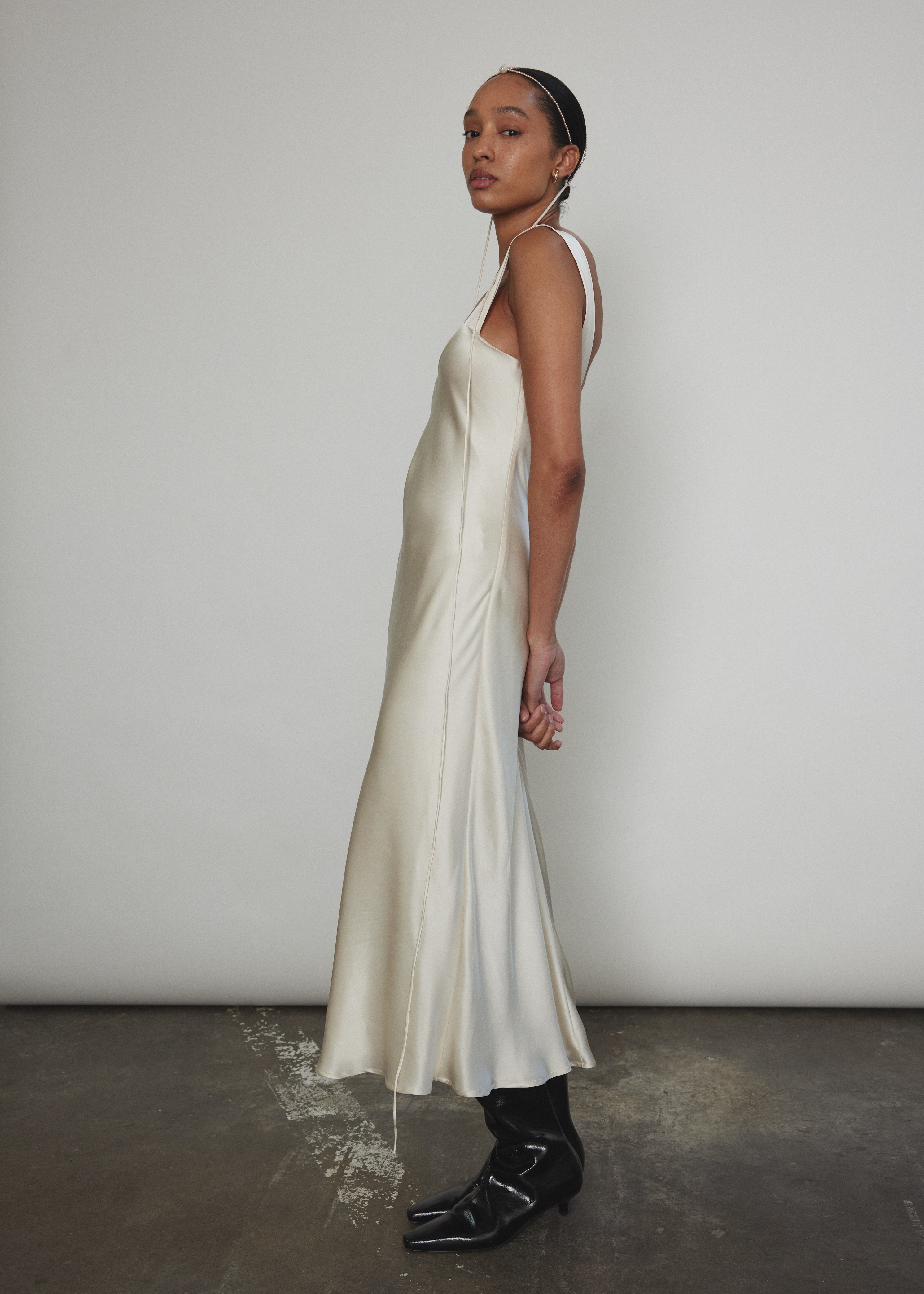 Side view of the ivory silk charmeuse Kamperett Lisette Midi Slip Dress, showing the bias-cut drape.