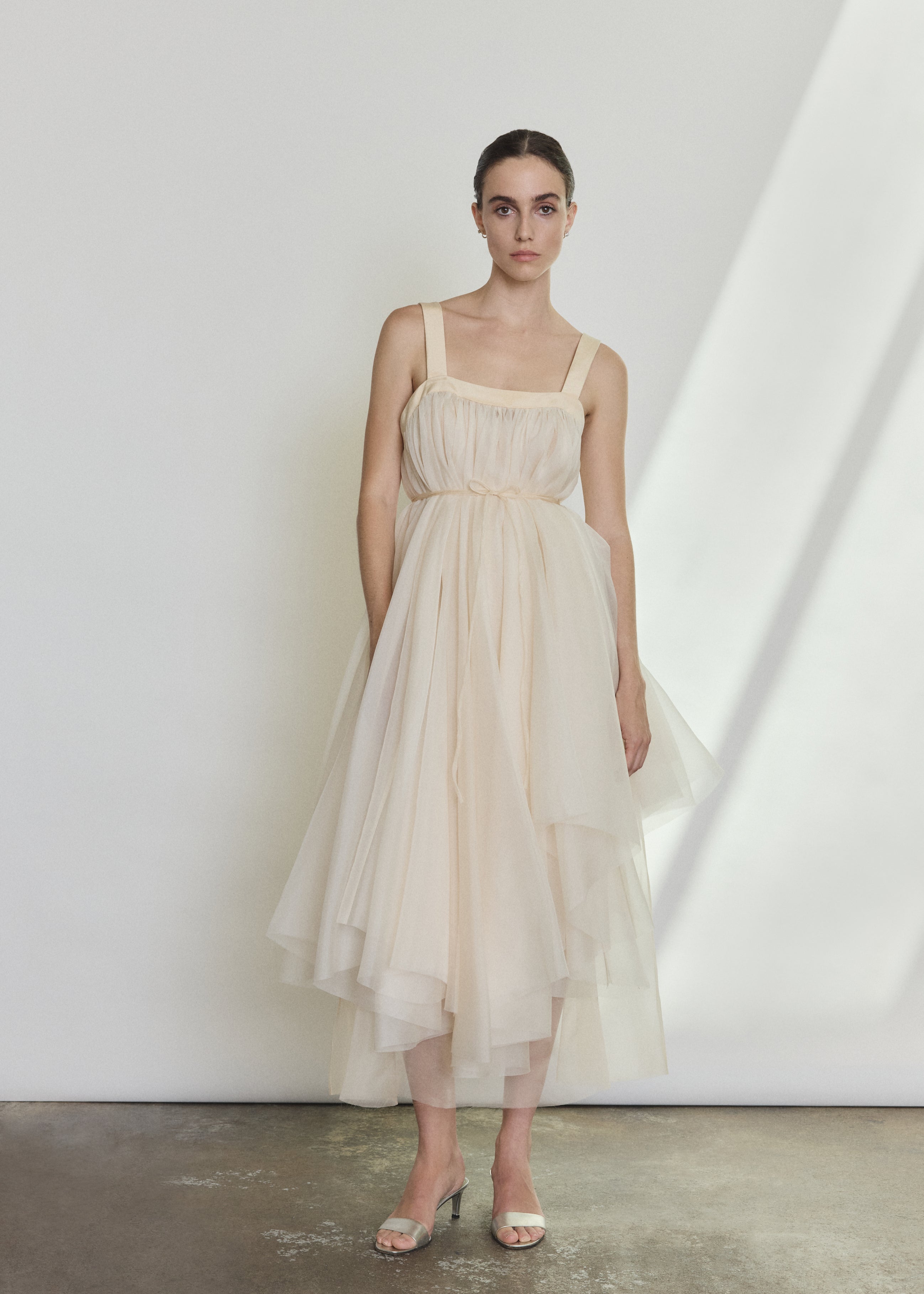 Detail of the ivory silk organza Kamperett Loie Dress showing the asymmetrical tier construction and silk cord waist.