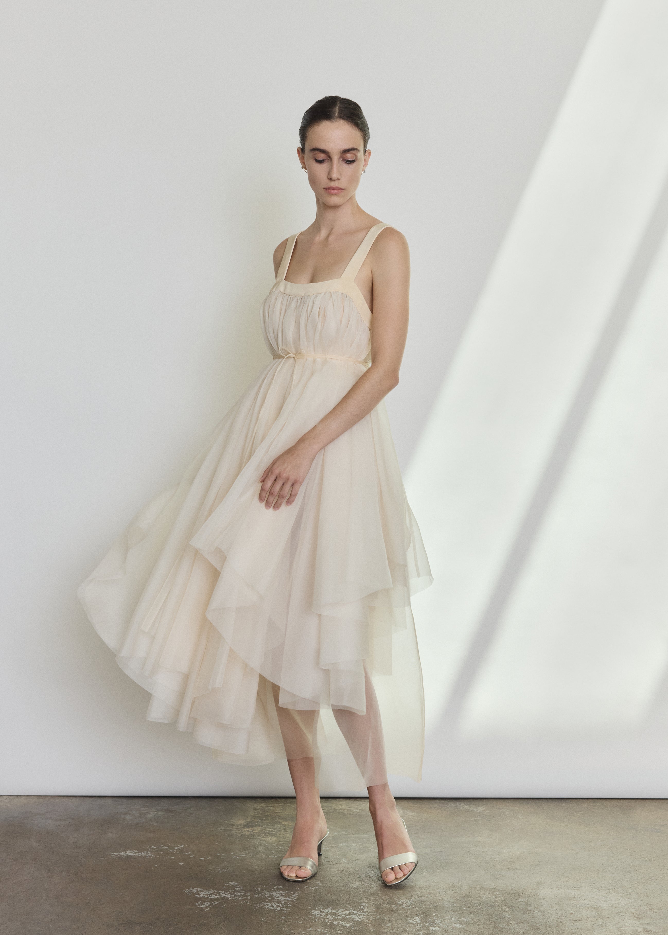 Editorial image of a bride wearing the ivory Kamperett Loie Dress, a modern bridal tiered silk organza midi.