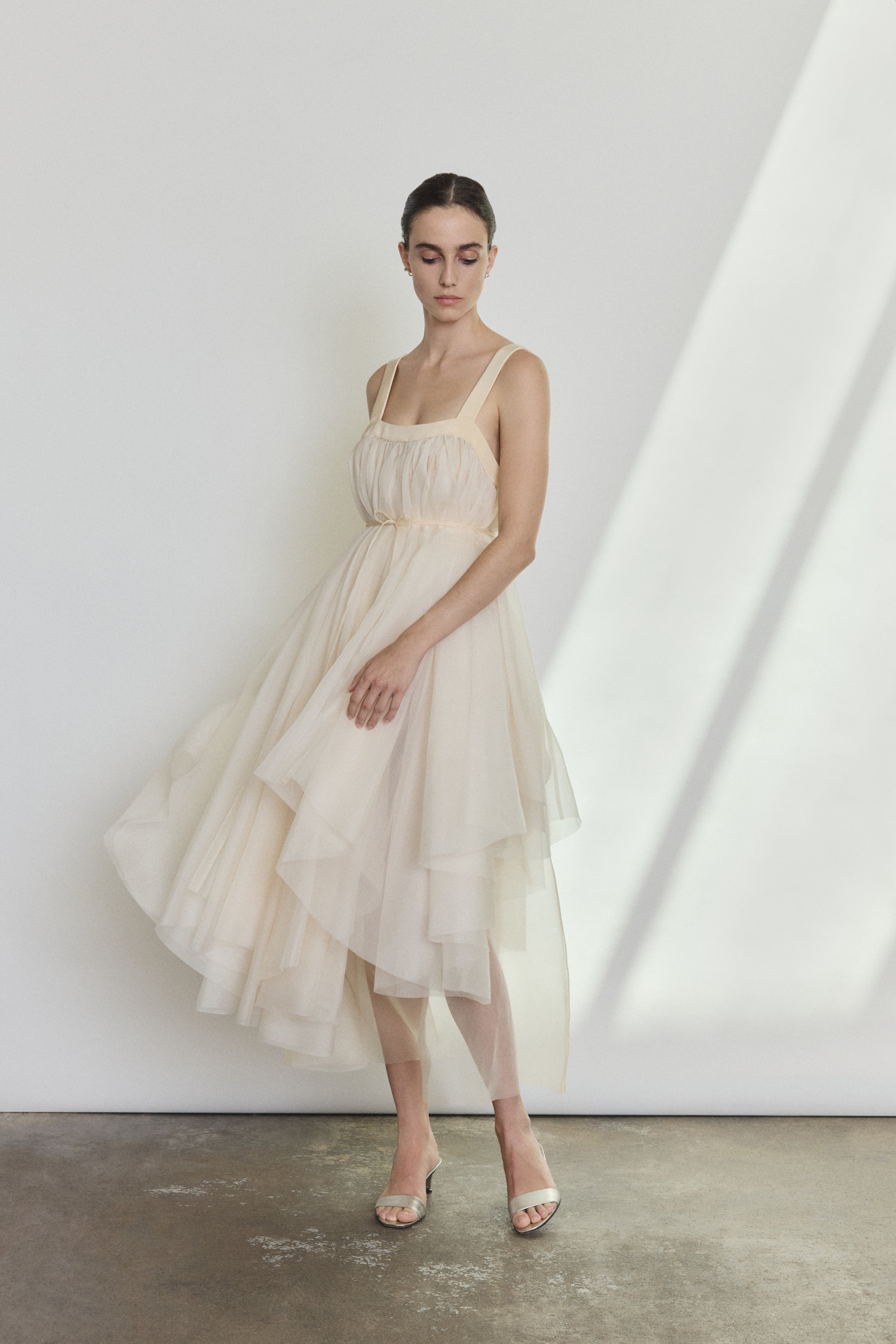 Editorial image of a bride wearing the ivory Kamperett Loie Dress, a modern bridal tiered silk organza midi.