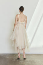 Editorial image of the ivory Kamperett Loie Dress showing the fluid tiered silhouette with cord waist untied.