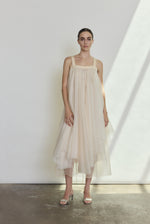 Front view of a bride wearing the ivory silk organza Kamperett Loie Dress, an asymmetrical tiered midi with square neckline and silk crepe straps.