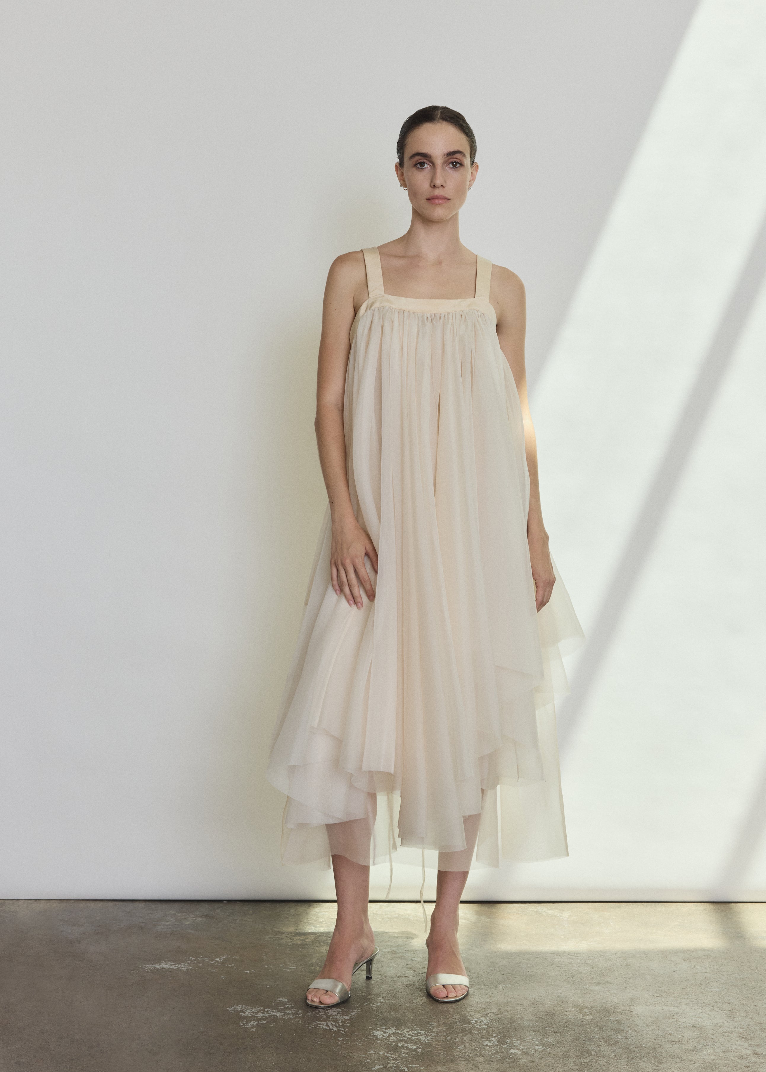 Front view of a bride wearing the ivory silk organza Kamperett Loie Dress, an asymmetrical tiered midi with square neckline and silk crepe straps.