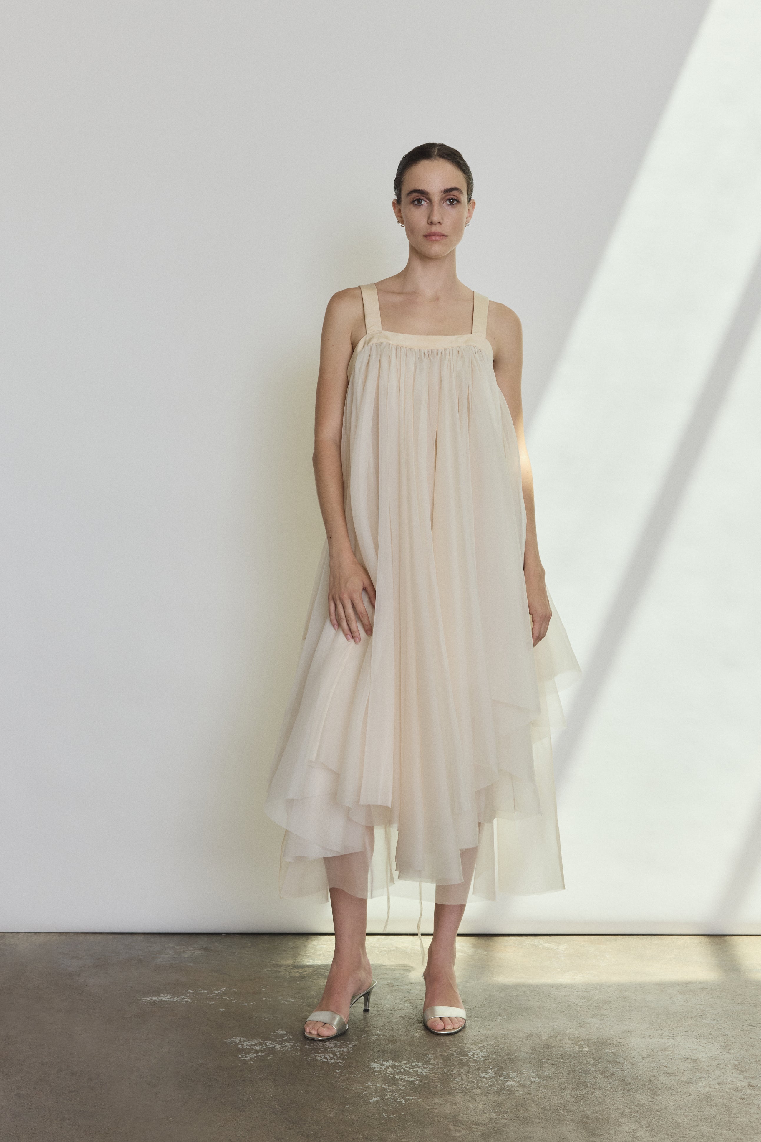 Front view of a bride wearing the ivory silk organza Kamperett Loie Dress, an asymmetrical tiered midi with square neckline and silk crepe straps.