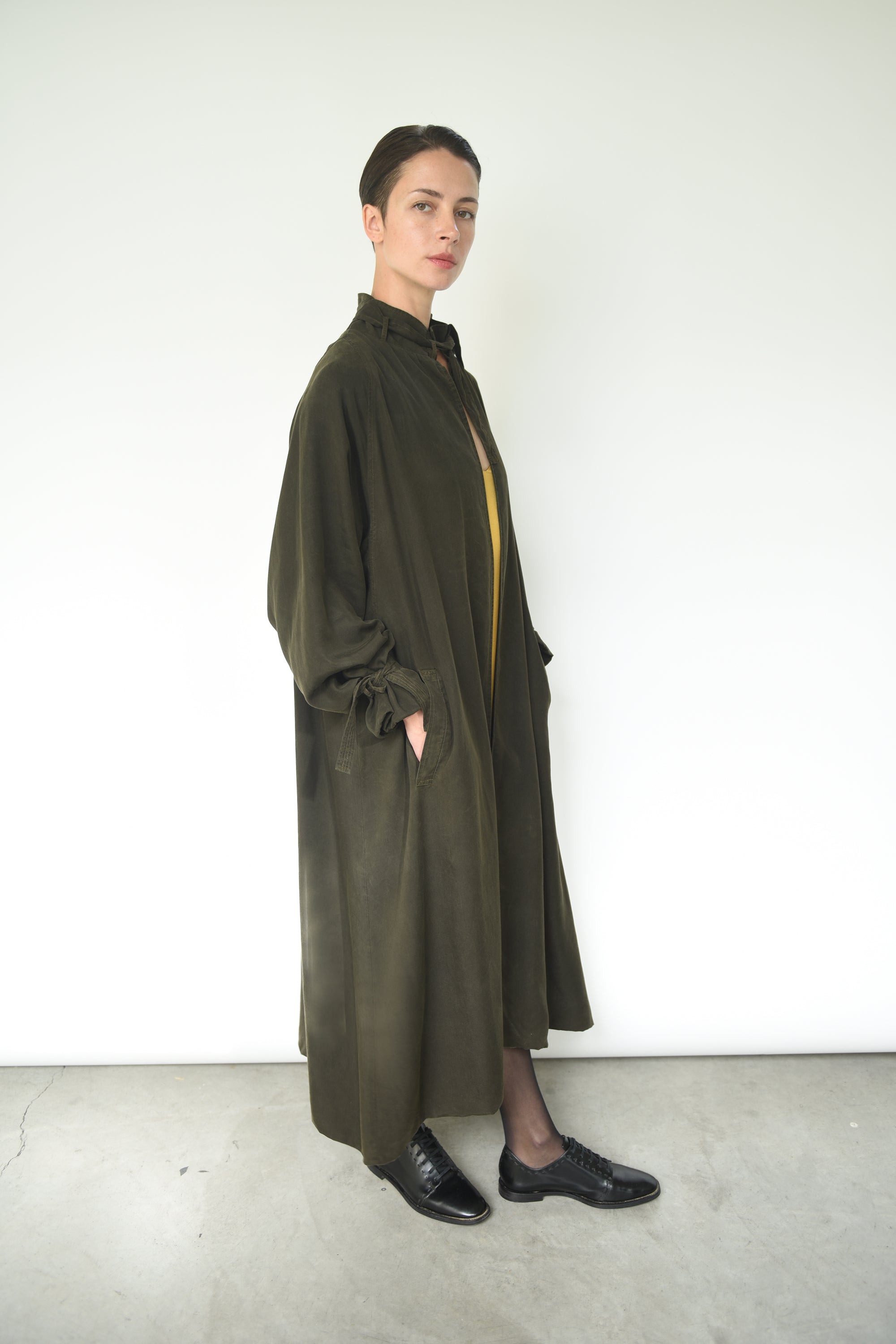 Angled view of the carob Lyocell Kamperett Lore Trench Coat showing the oversized swing silhouette.