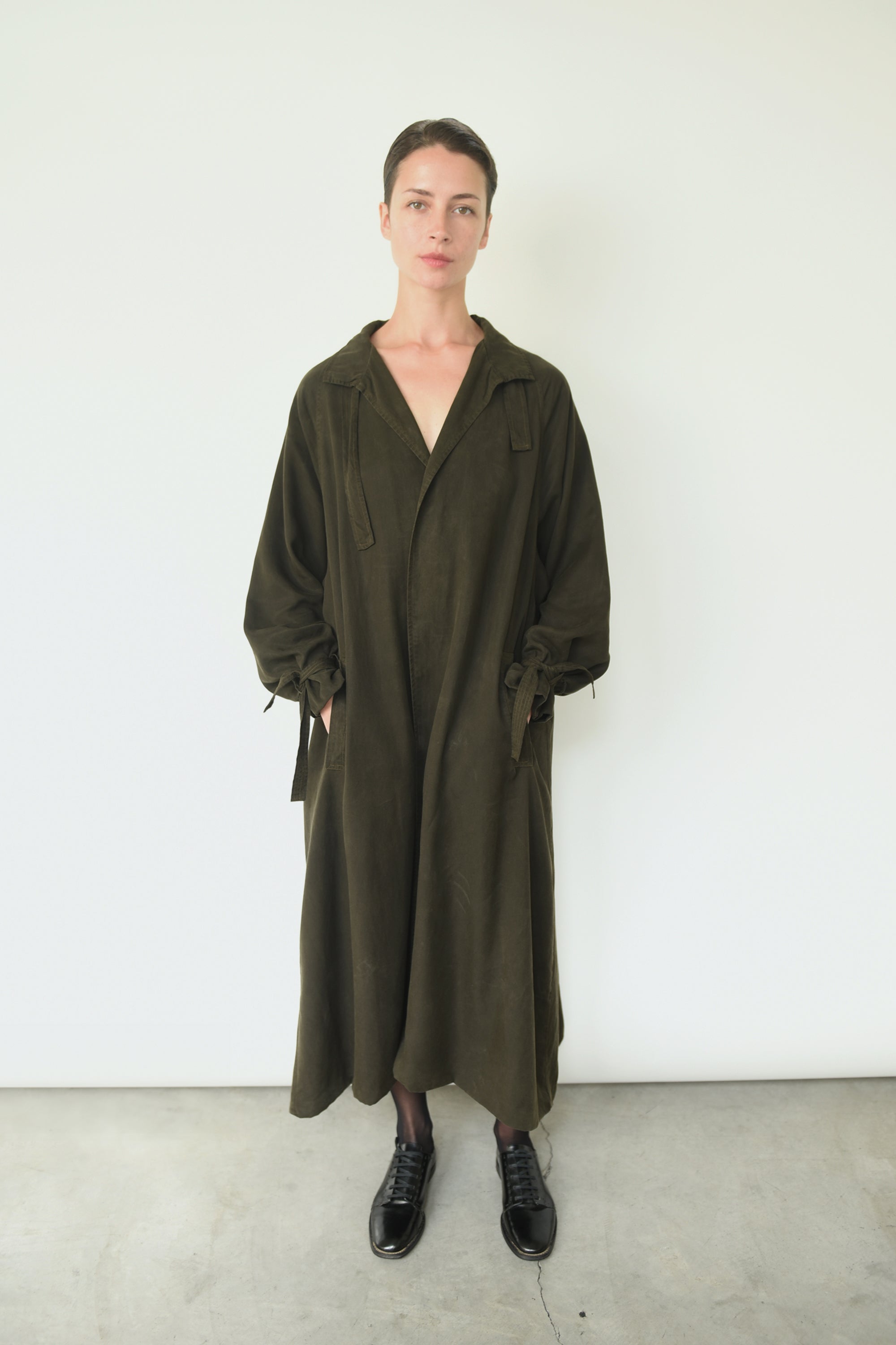 Front view of a model wearing the carob Lyocell Kamperett Lore Trench Coat, an oversized swing trench with mandarin collar.