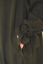 Motion shot of the carob Lyocell Kamperett Lore Trench Coat, capturing the swing silhouette and full raglan sleeves.