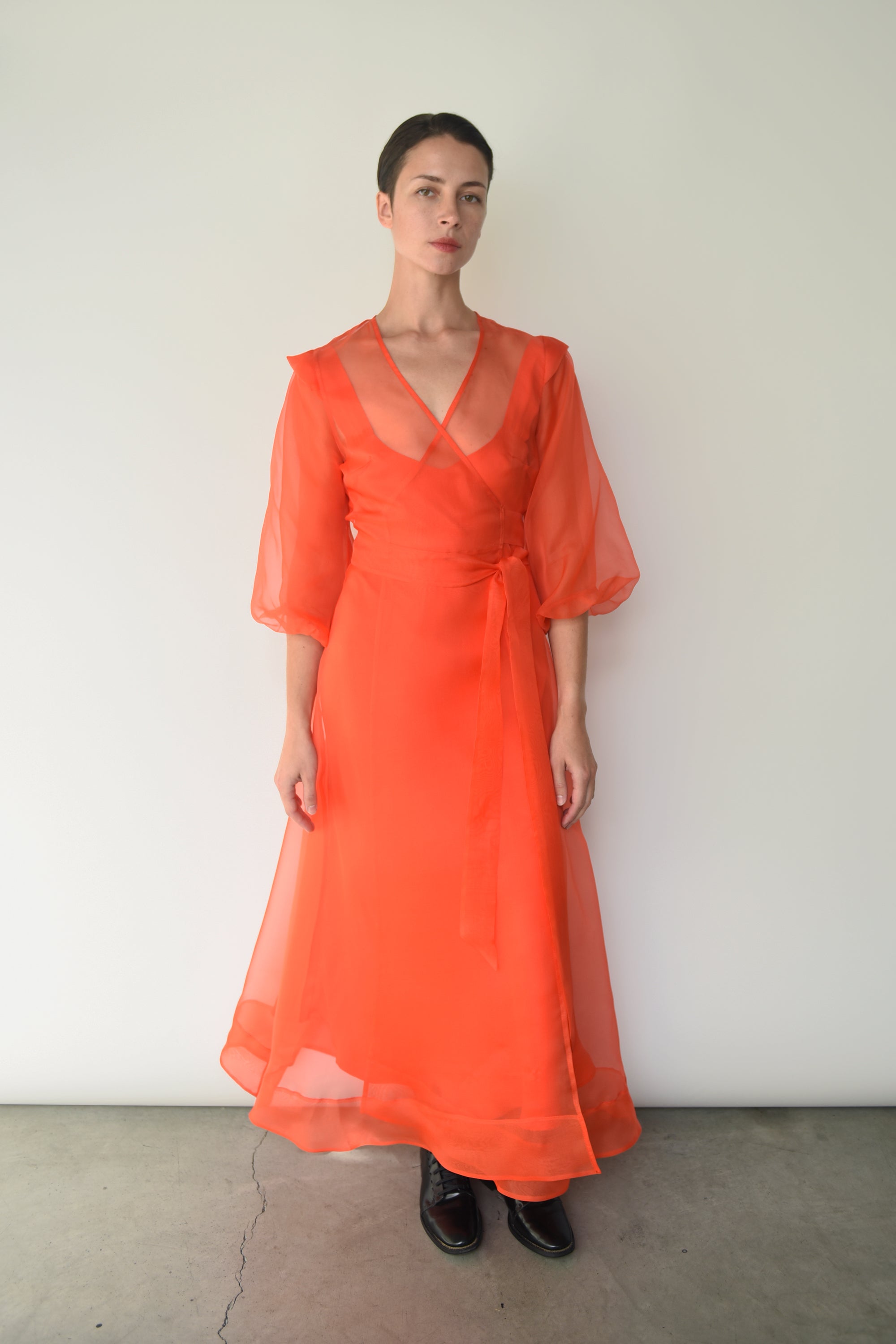 Angled view of the vermilion silk organza Kamperett Loretta Midi Dress showing the wrap closure.