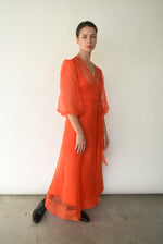 Front view of a model wearing the vermilion silk organza Kamperett Loretta Midi Dress, a wrap with elbow-length sleeves and shoulder ruffle.