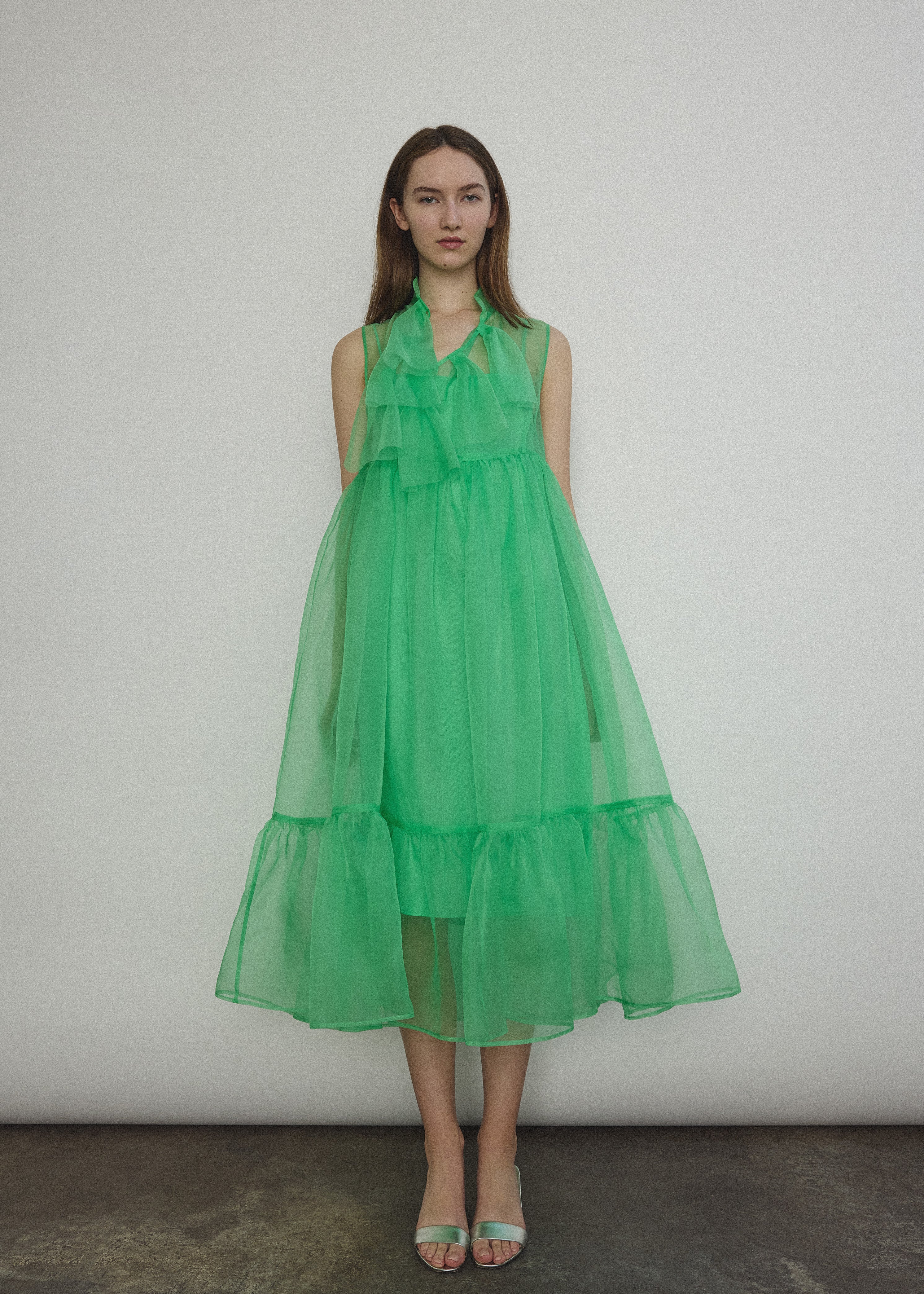 Front view of a model wearing the celadon silk organza Kamperett Mae Dress, a midi with empire waist and qipao-inspired tie front.