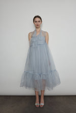 Front view of a model wearing the powder blue silk organza Kamperett Mae Dress, a midi with empire waist and qipao-inspired tie front.