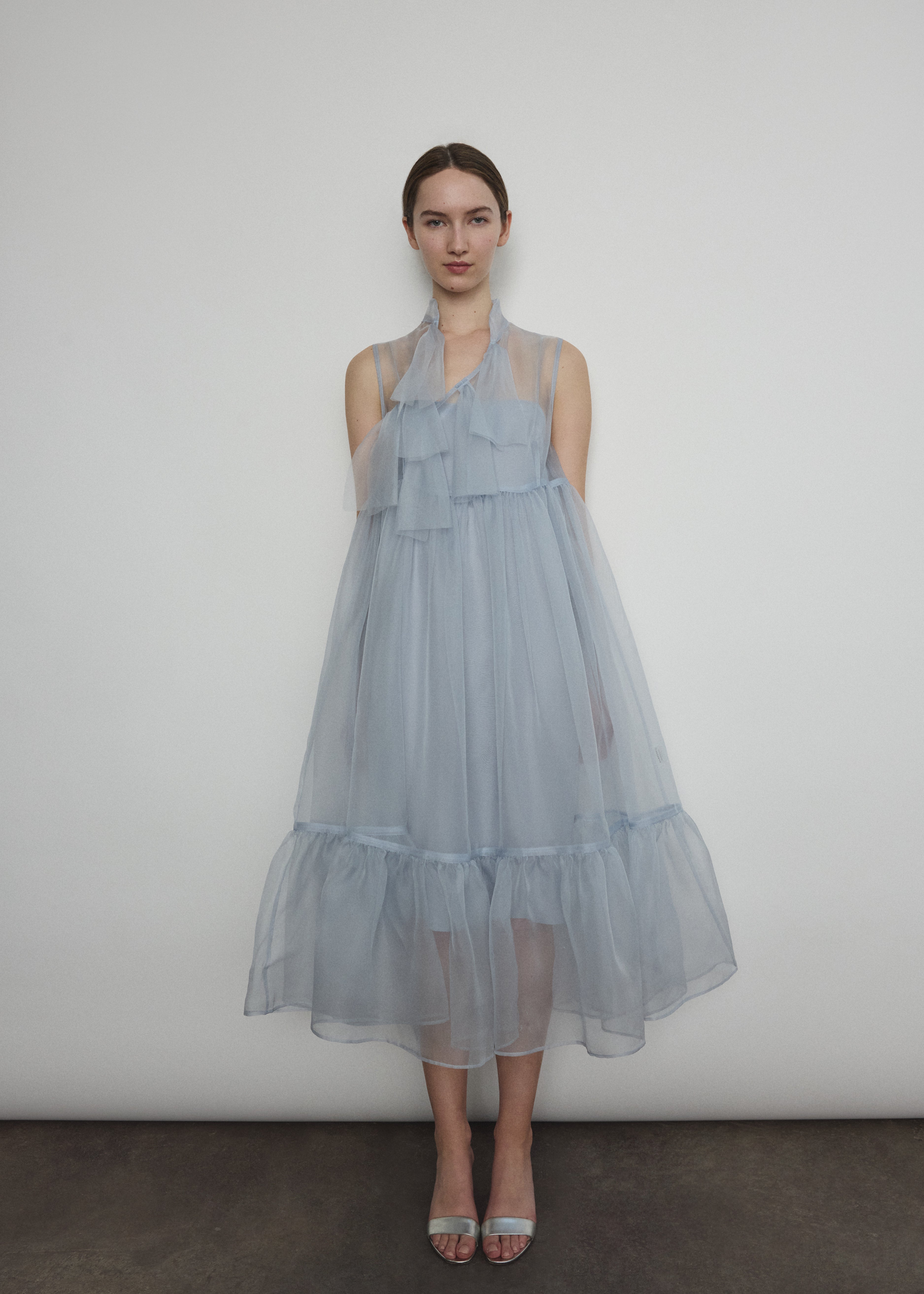 Front view of a model wearing the powder blue silk organza Kamperett Mae Dress, a midi with empire waist and qipao-inspired tie front.