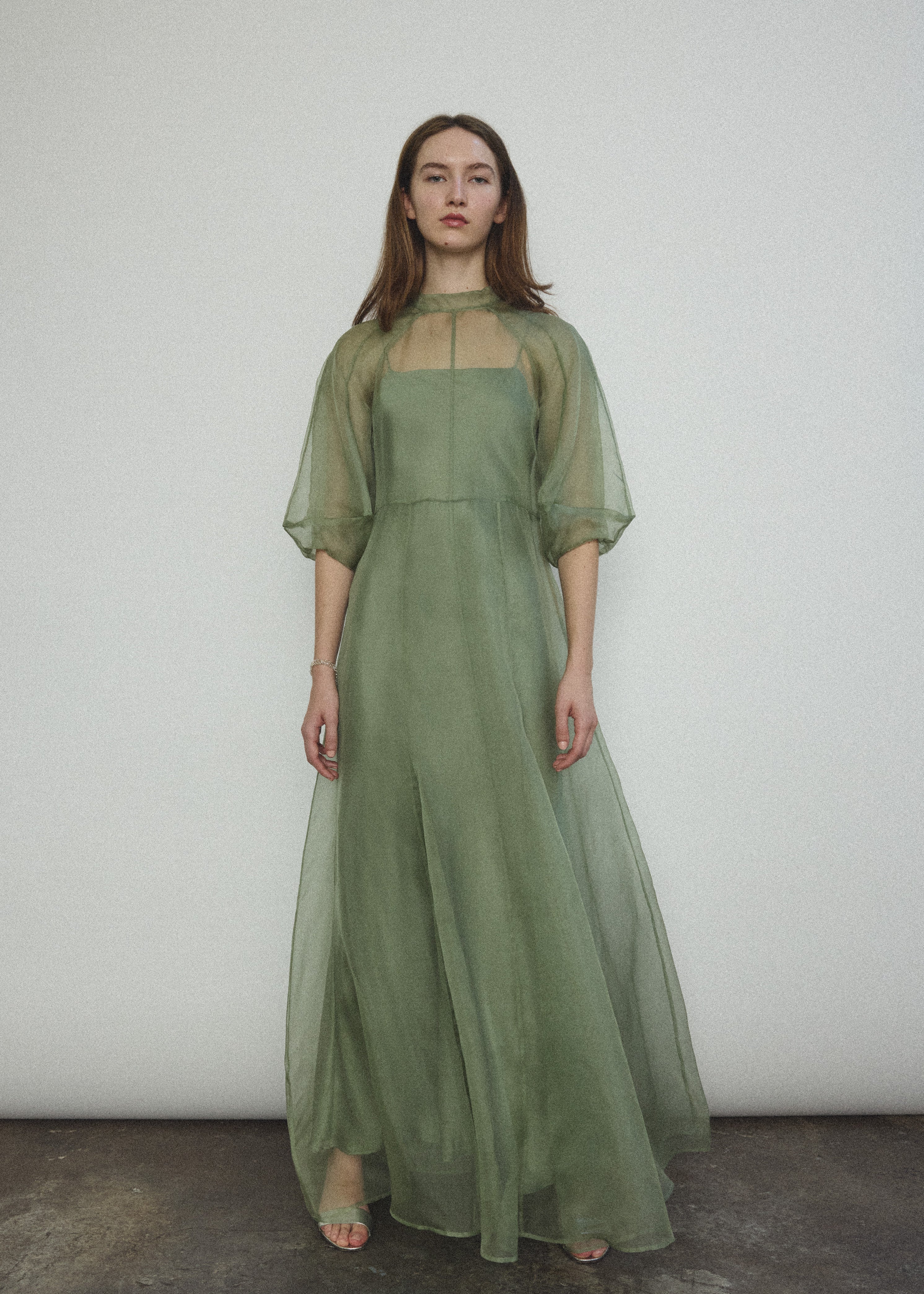 Front view of a model wearing the jade silk organza Kamperett Meiere Gown, with architectural sleeves and fitted waist.