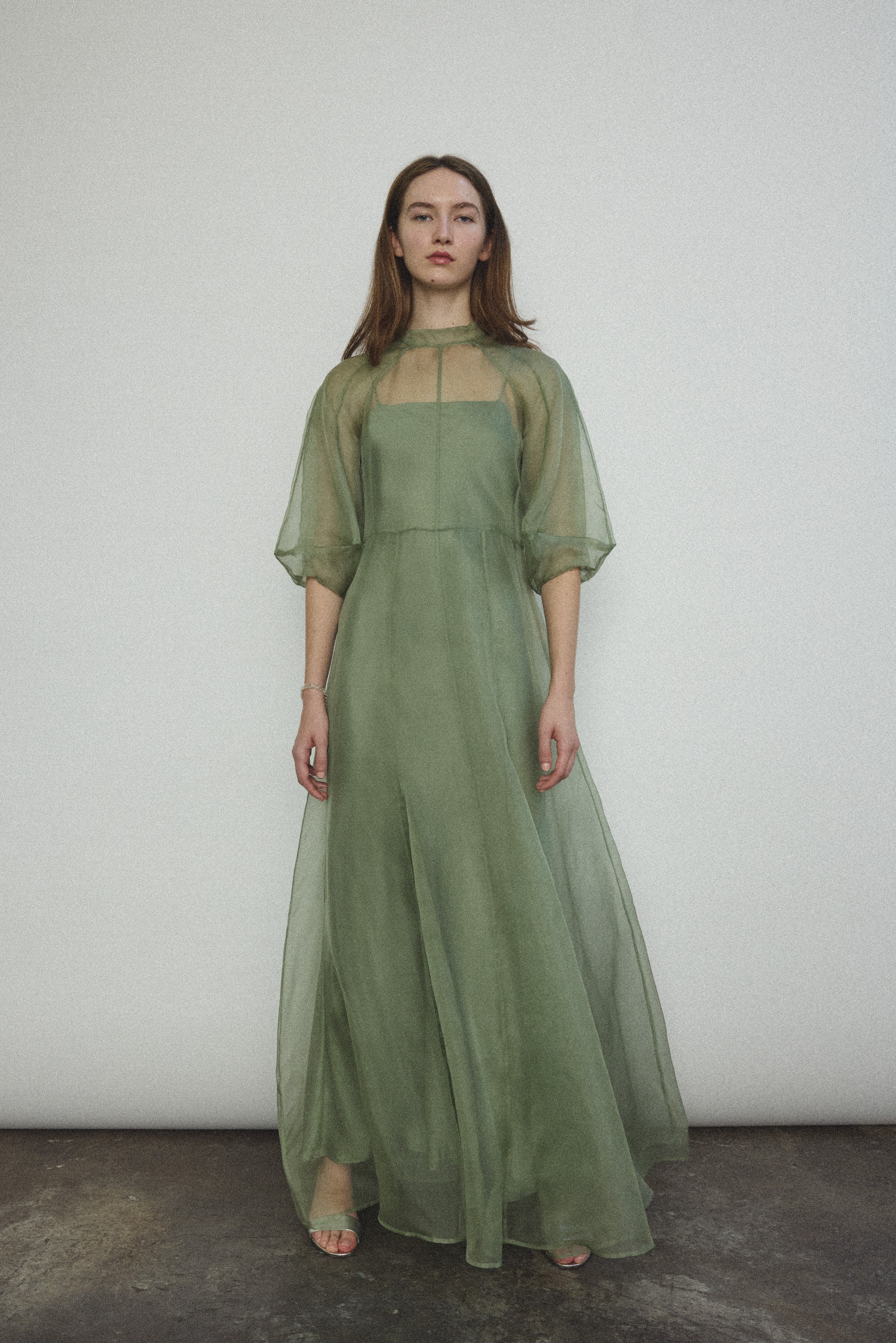 Front view of a model wearing the jade silk organza Kamperett Meiere Gown, with architectural sleeves and fitted waist.