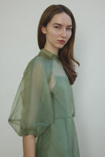 Motion shot of the jade silk organza Kamperett Meiere Gown, capturing the sweeping multi-godet skirt.
