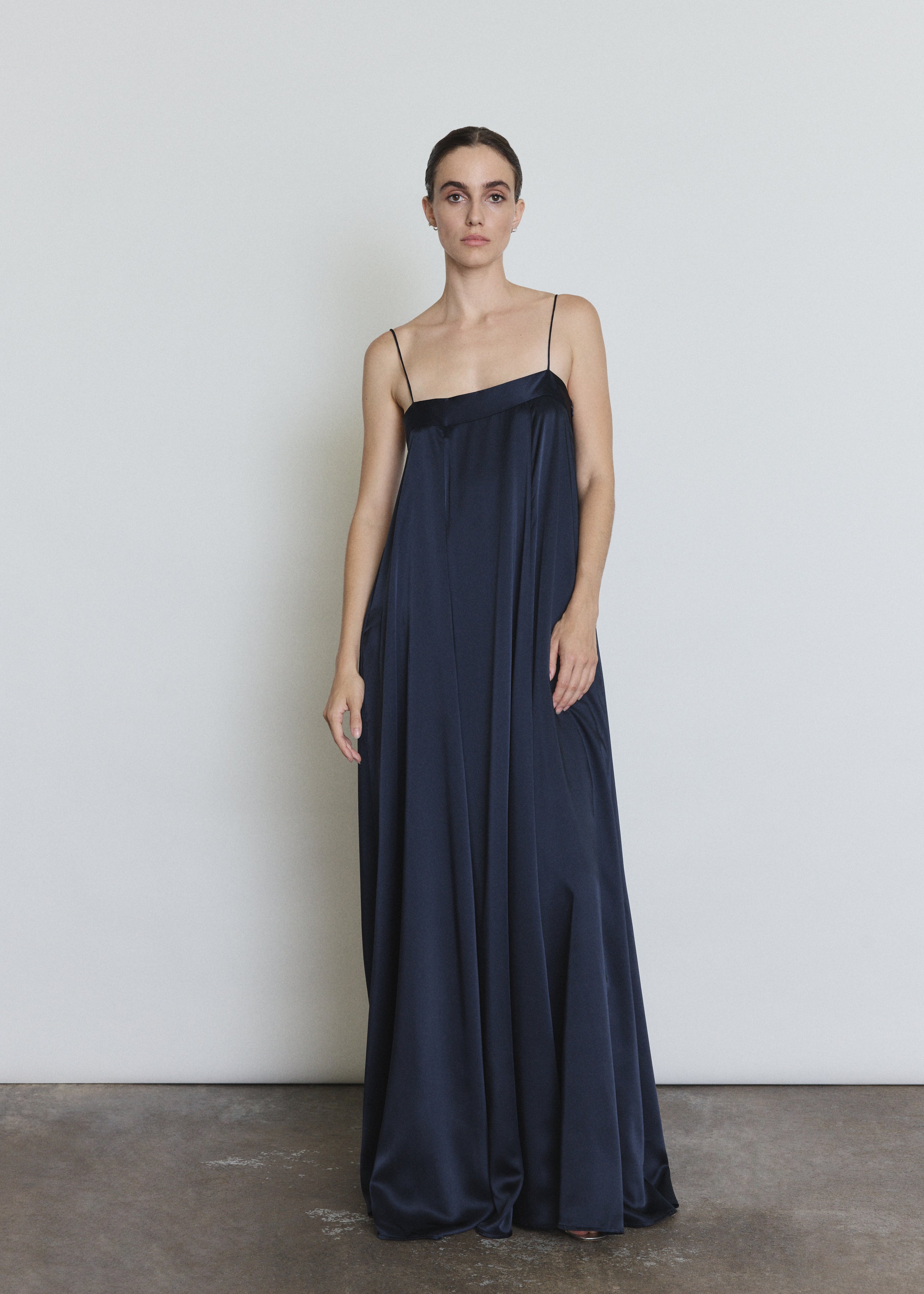 Front view of a model wearing the midnight silk Kamperett Metronome Gown, a sleek column gown with sweeping hem and corded straps.