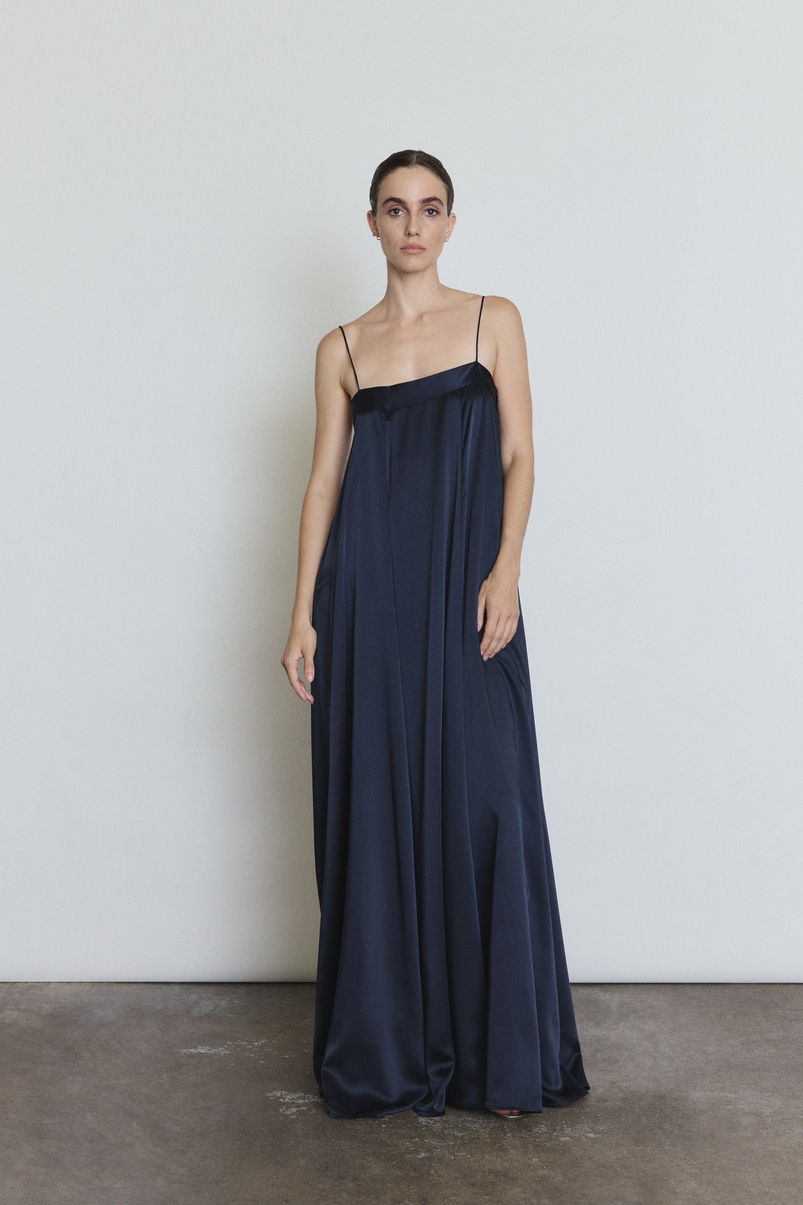 Front view of a model wearing the midnight silk Kamperett Metronome Gown, a sleek column gown with sweeping hem and corded straps.