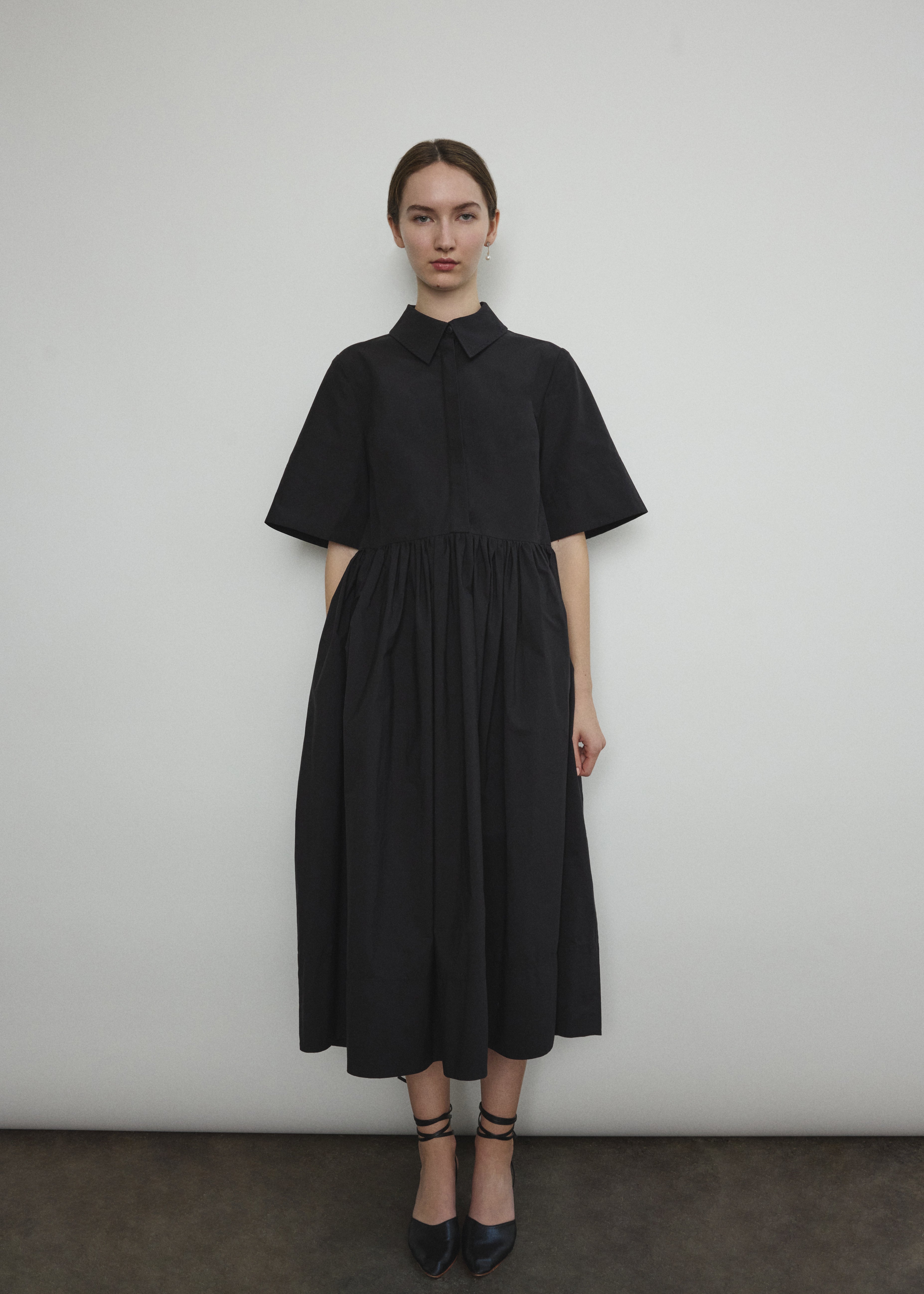 Front view of a model wearing the black Japanese cotton lawn Kamperett Miller Dress, an oversized shirt dress with button front.