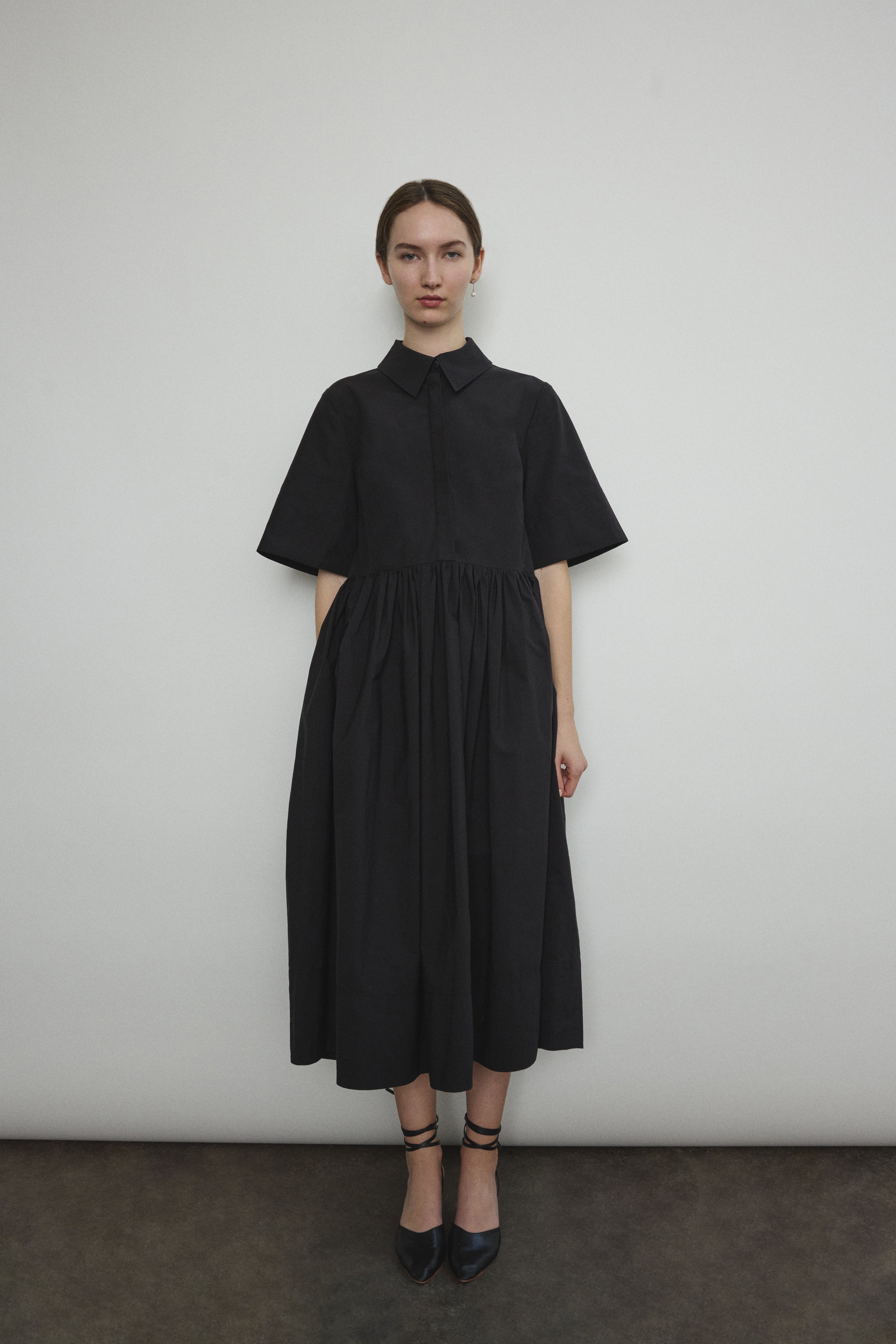 Front view of a model wearing the black Japanese cotton lawn Kamperett Miller Dress, an oversized shirt dress with button front.