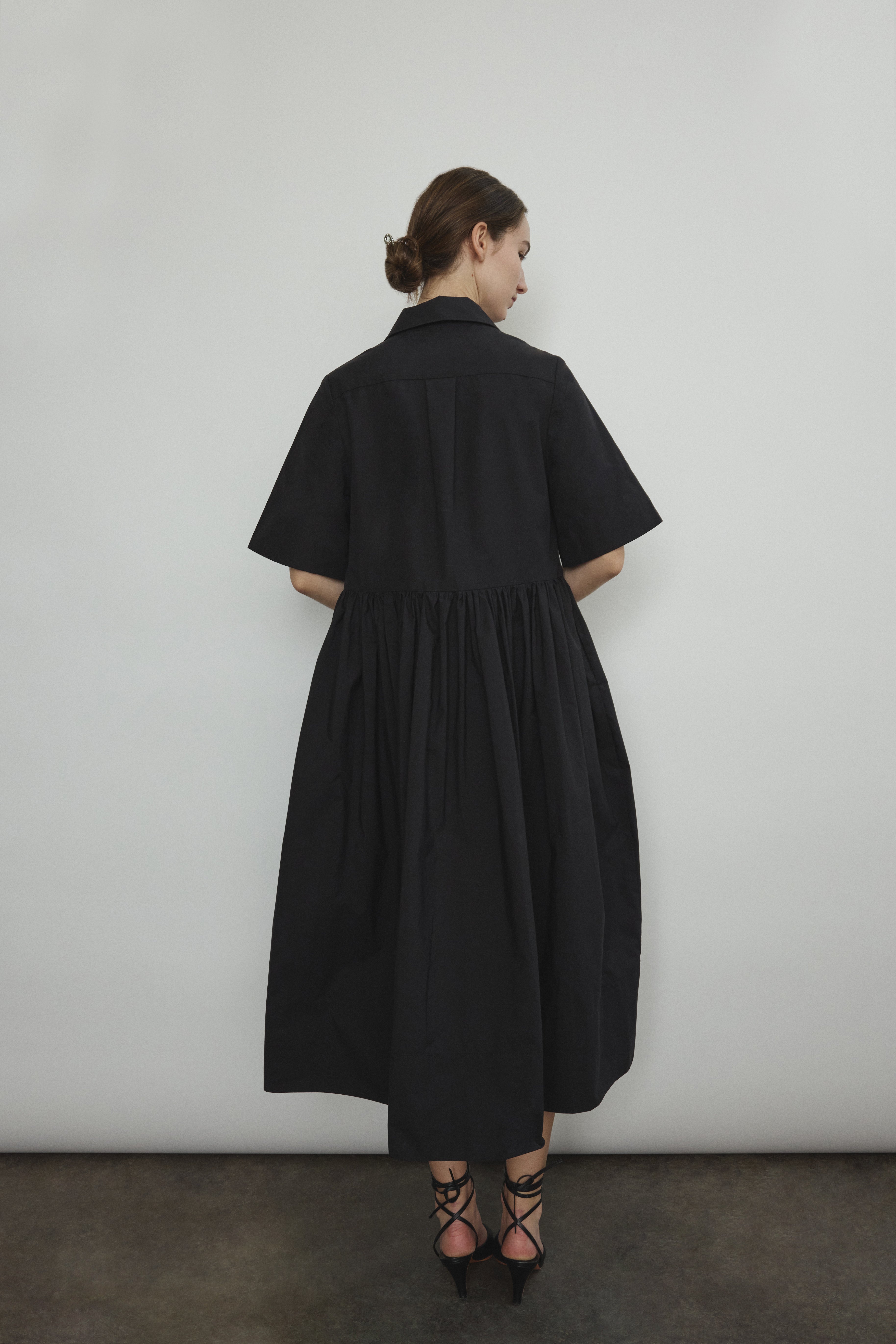 Side view of the black Japanese cotton lawn Kamperett Miller Dress with gathered waist and short sleeves.
