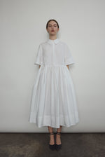 Front view of a model wearing the white Japanese cotton lawn Kamperett Miller Dress, an oversized shirt dress with button front.