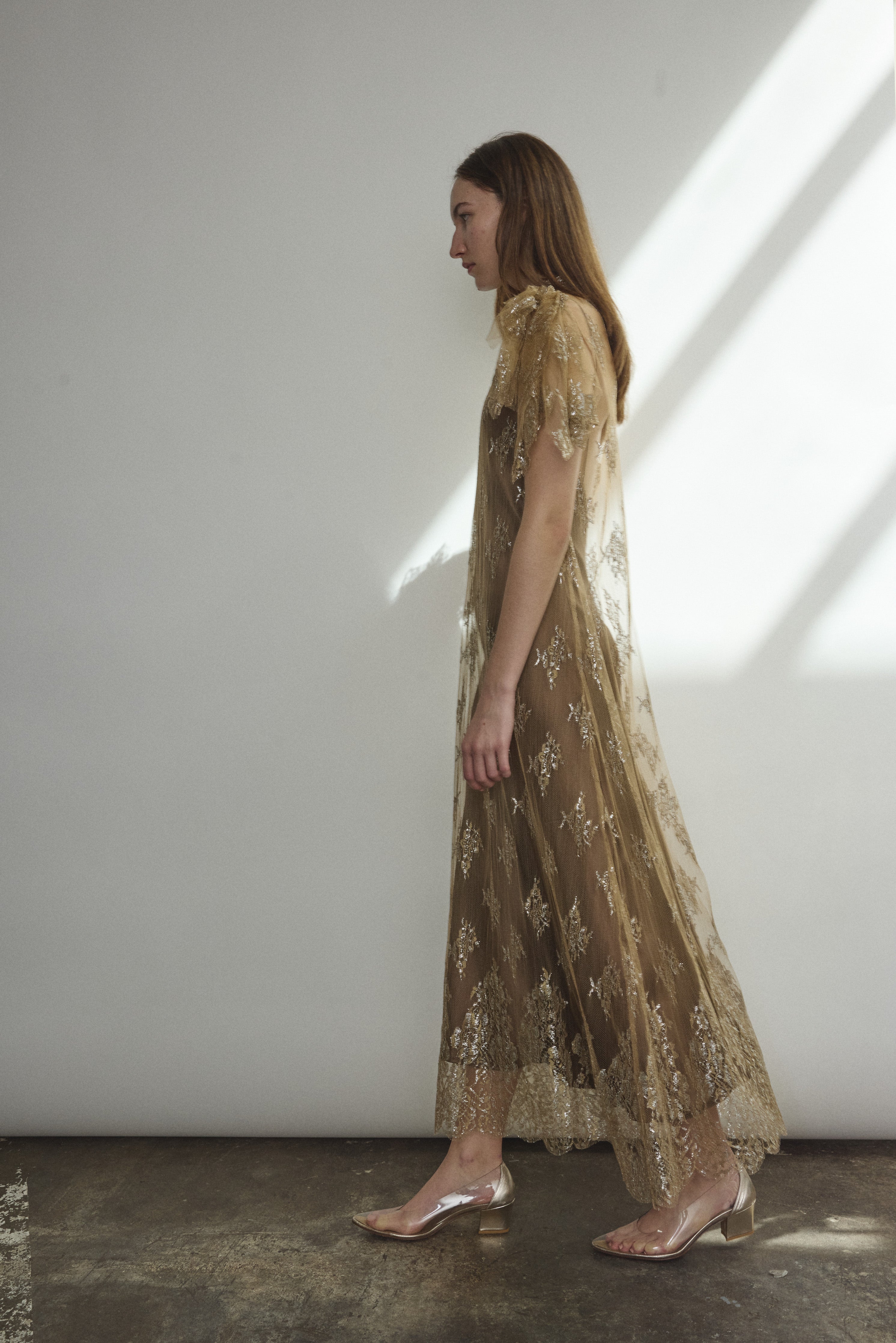 Left profile of Kamperett Moony Lace Gown in mink French lace, straight sheath silhouette with deconstructed cap sleeve and soft metallic detailing.