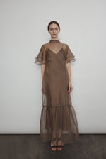 Model in a voluminous mushroom silk organza Barre maxi dress with oversized ruffles and tiered sleeves.