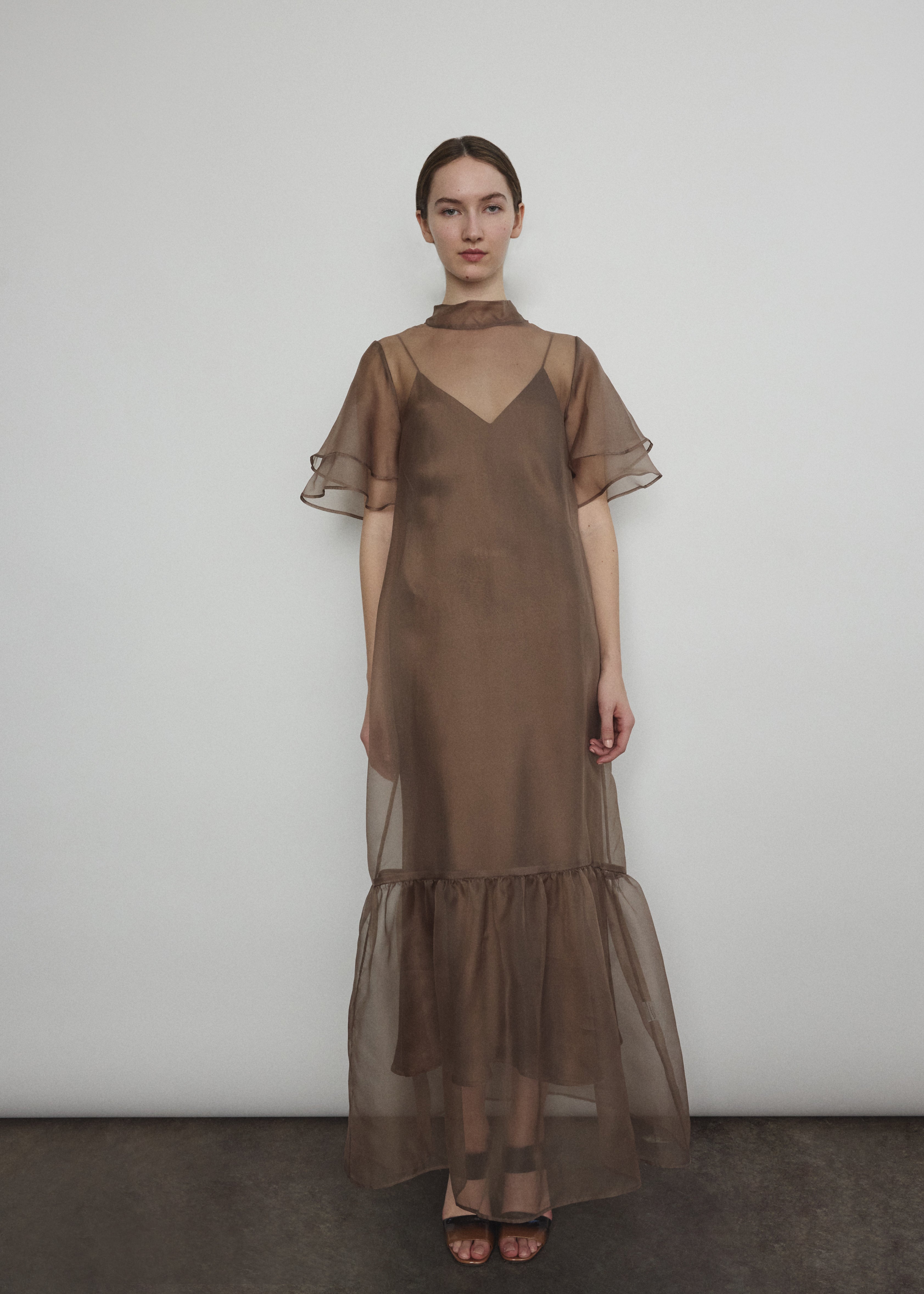 Model in a voluminous mushroom silk organza Barre maxi dress with oversized ruffles and tiered sleeves.