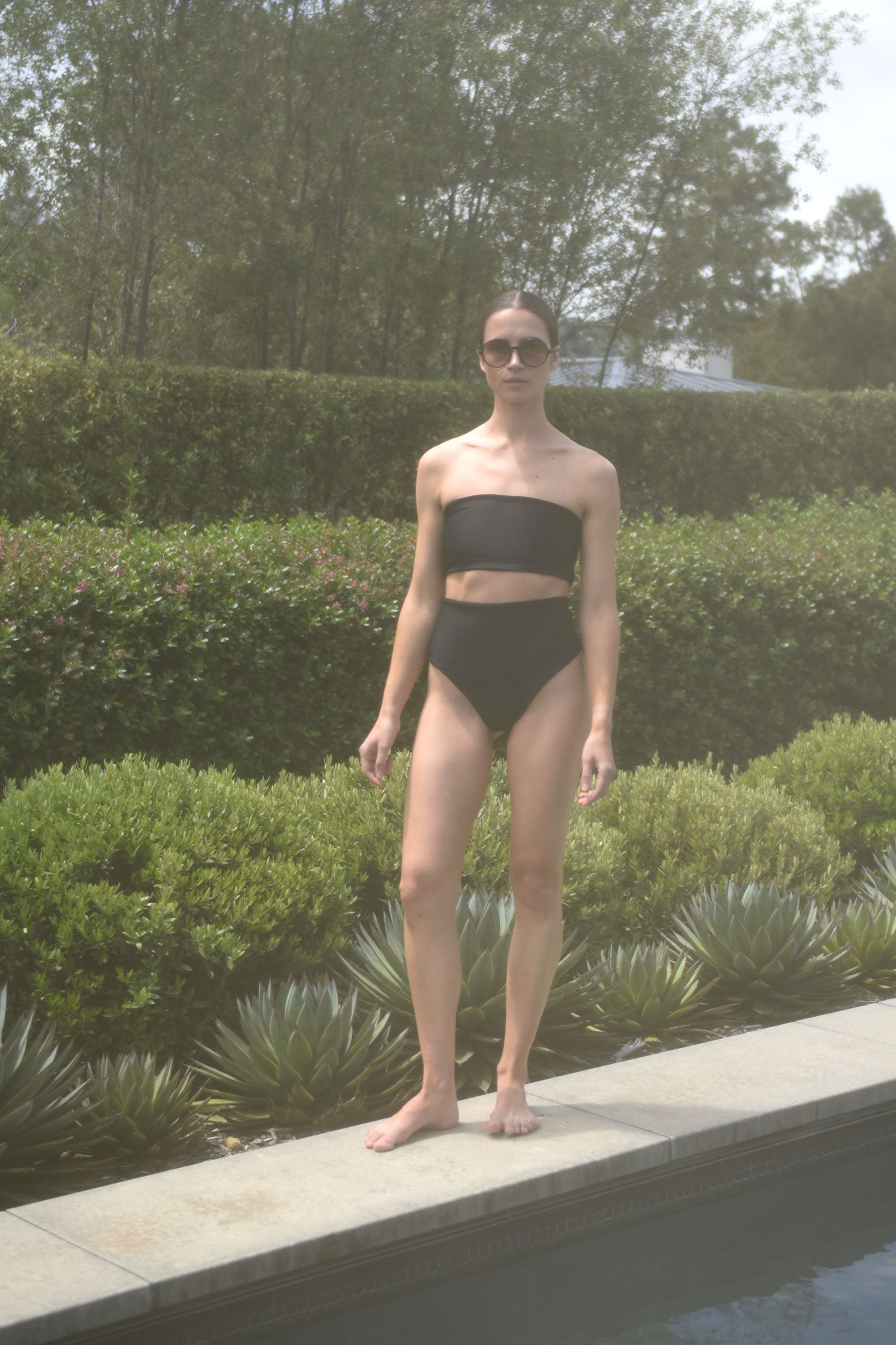 Editorial image of a model in the black Italian regenerated nylon Kamperett Orra Bandeau Top.