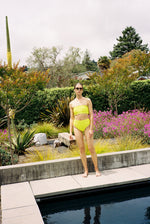 Editorial image of a model in the chartreuse Italian regenerated nylon Kamperett Orra High Waist Brief.