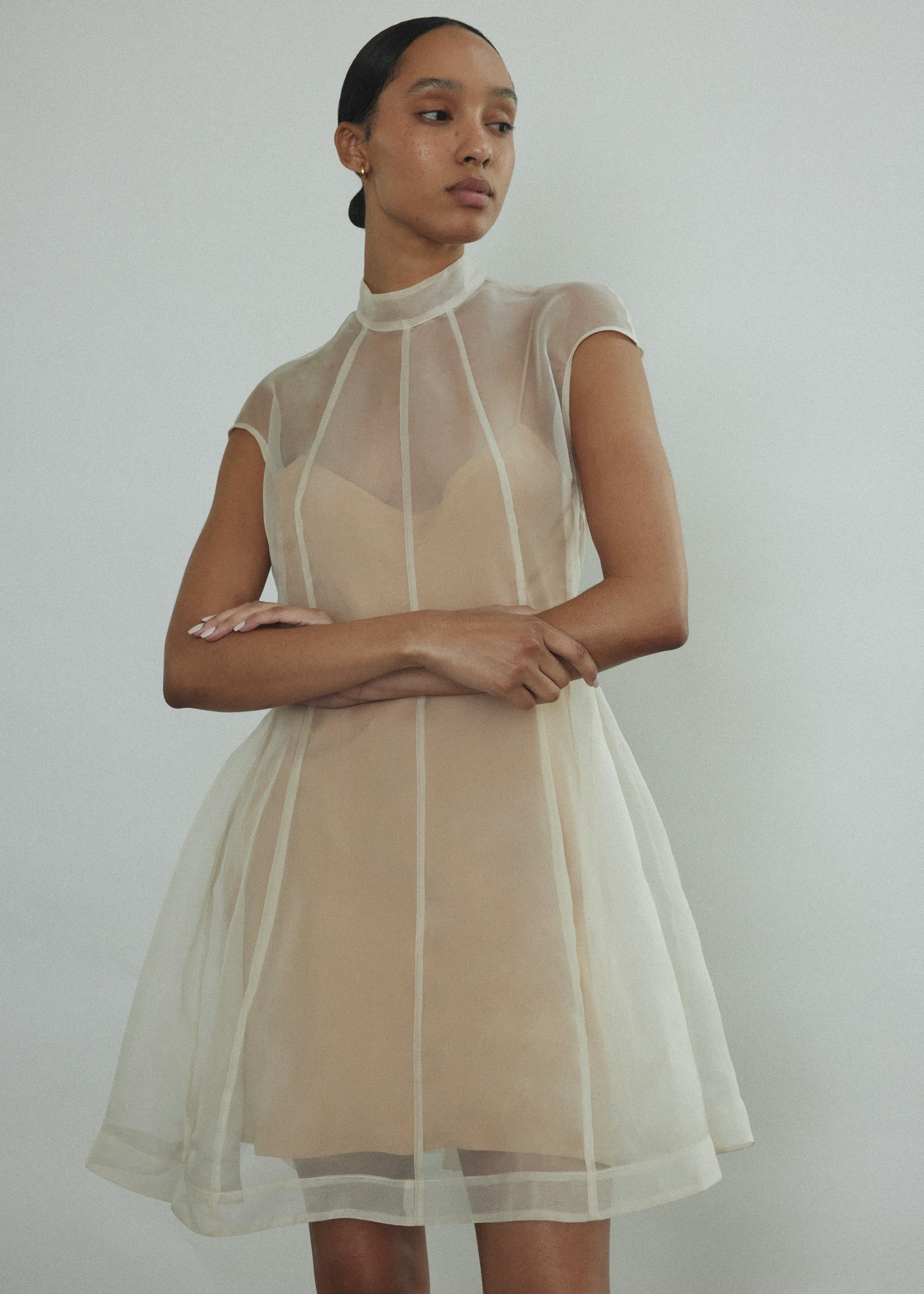 Front view of a bride wearing the ivory silk organza Kamperett Reine Dress, an intricately seamed mini with mock neck.