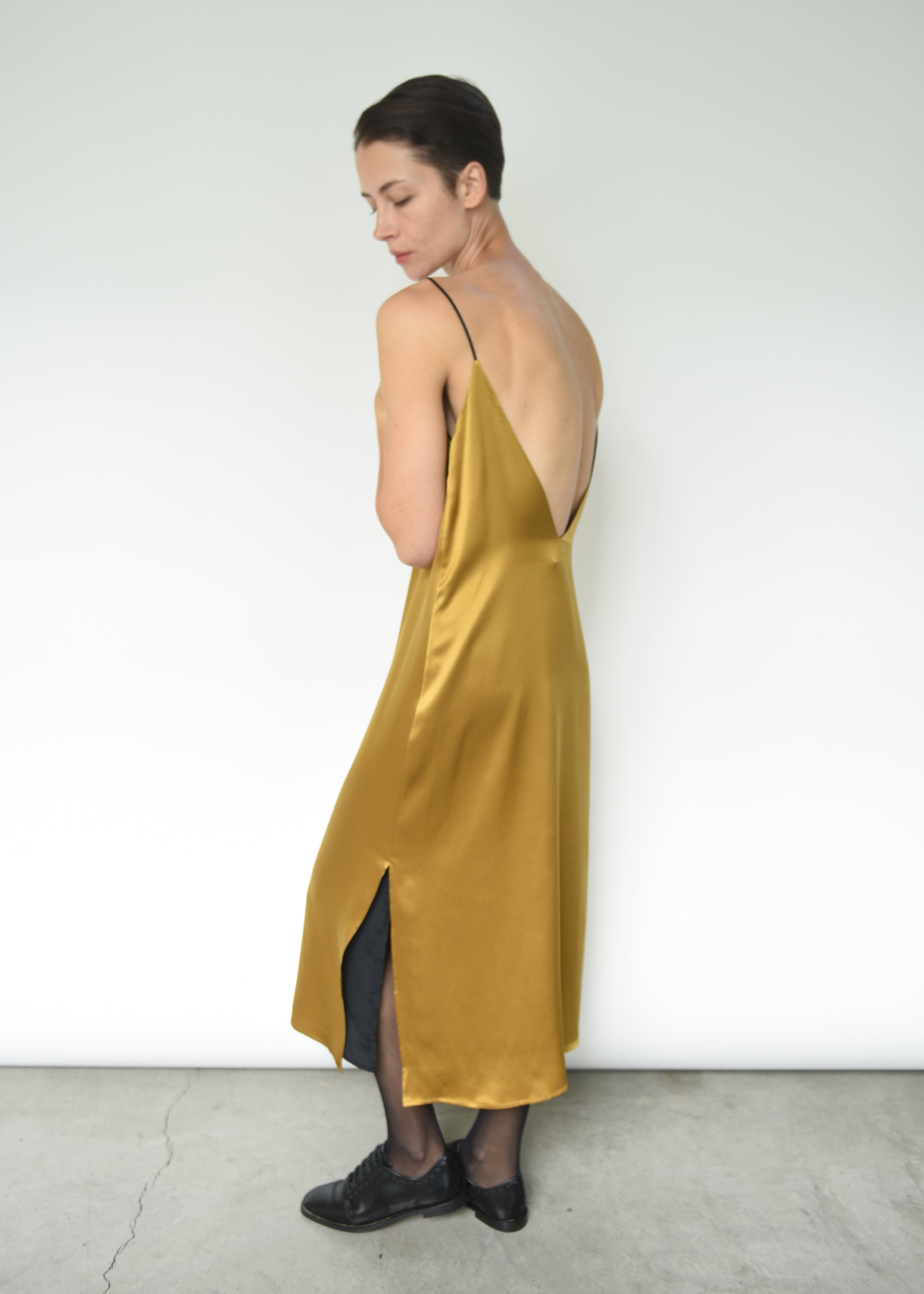 Angled view of the brass silk charmeuse Kamperett Sade Slip Dress.