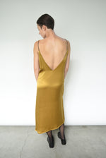 Back-angled view of the brass silk charmeuse Kamperett Sade Slip Dress.