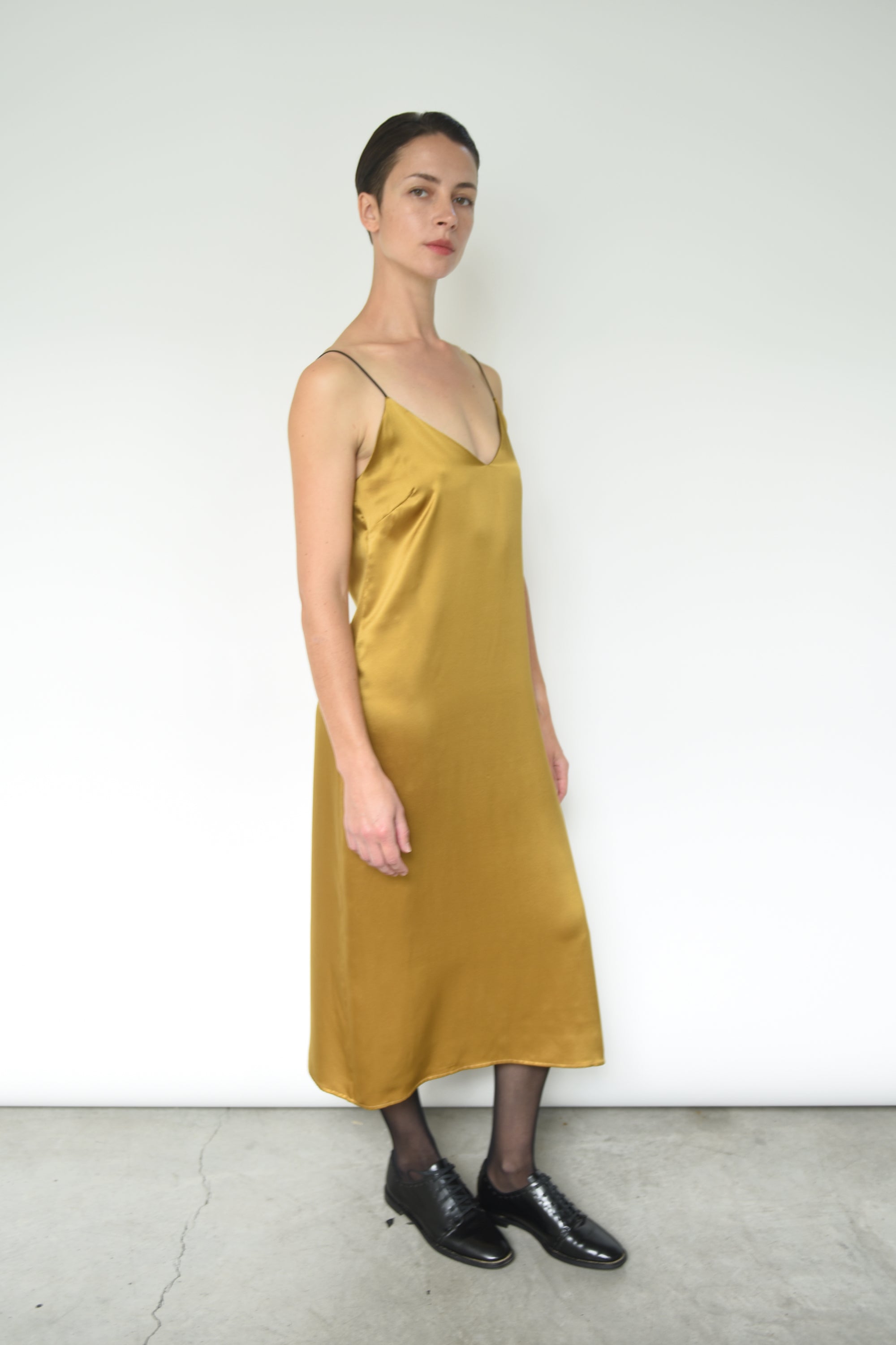 Detail of the dramatic V back on the brass silk charmeuse Kamperett Sade Slip Dress.
