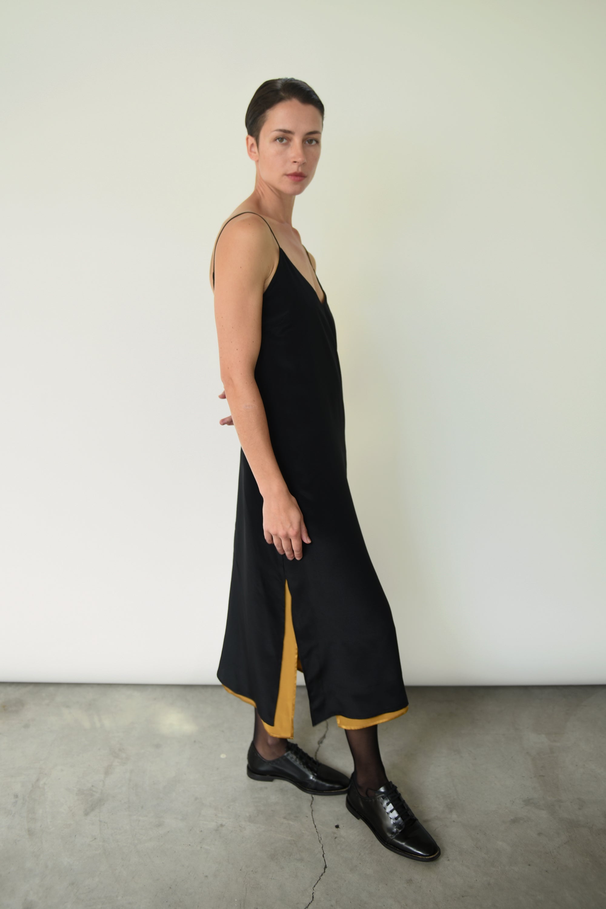 Editorial angled shot of the brass silk charmeuse Kamperett Sade Slip Dress.