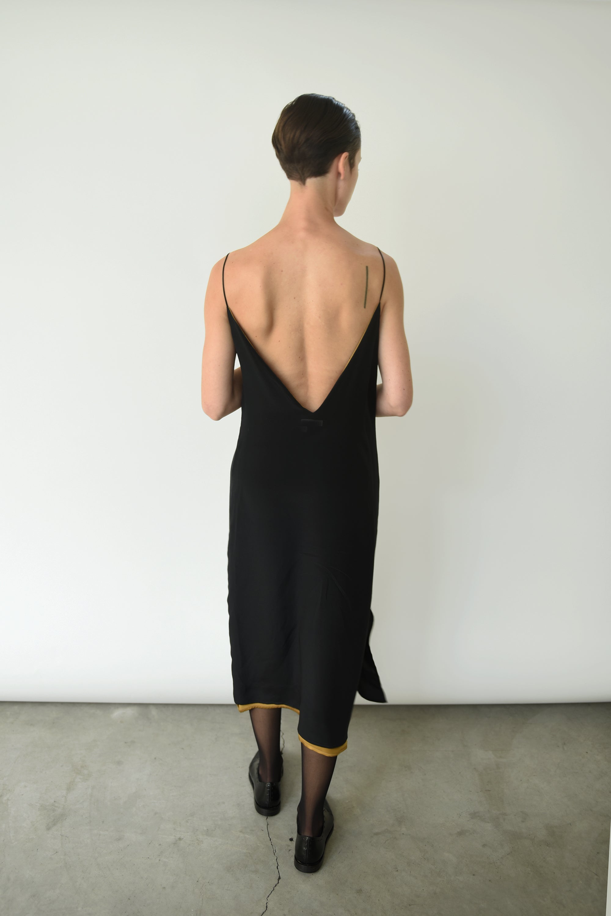 Editorial seated shot of the brass silk charmeuse Kamperett Sade Slip Dress.