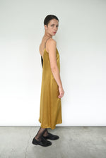 Side view of the brass silk charmeuse Kamperett Sade Slip Dress, showing the loose silhouette.